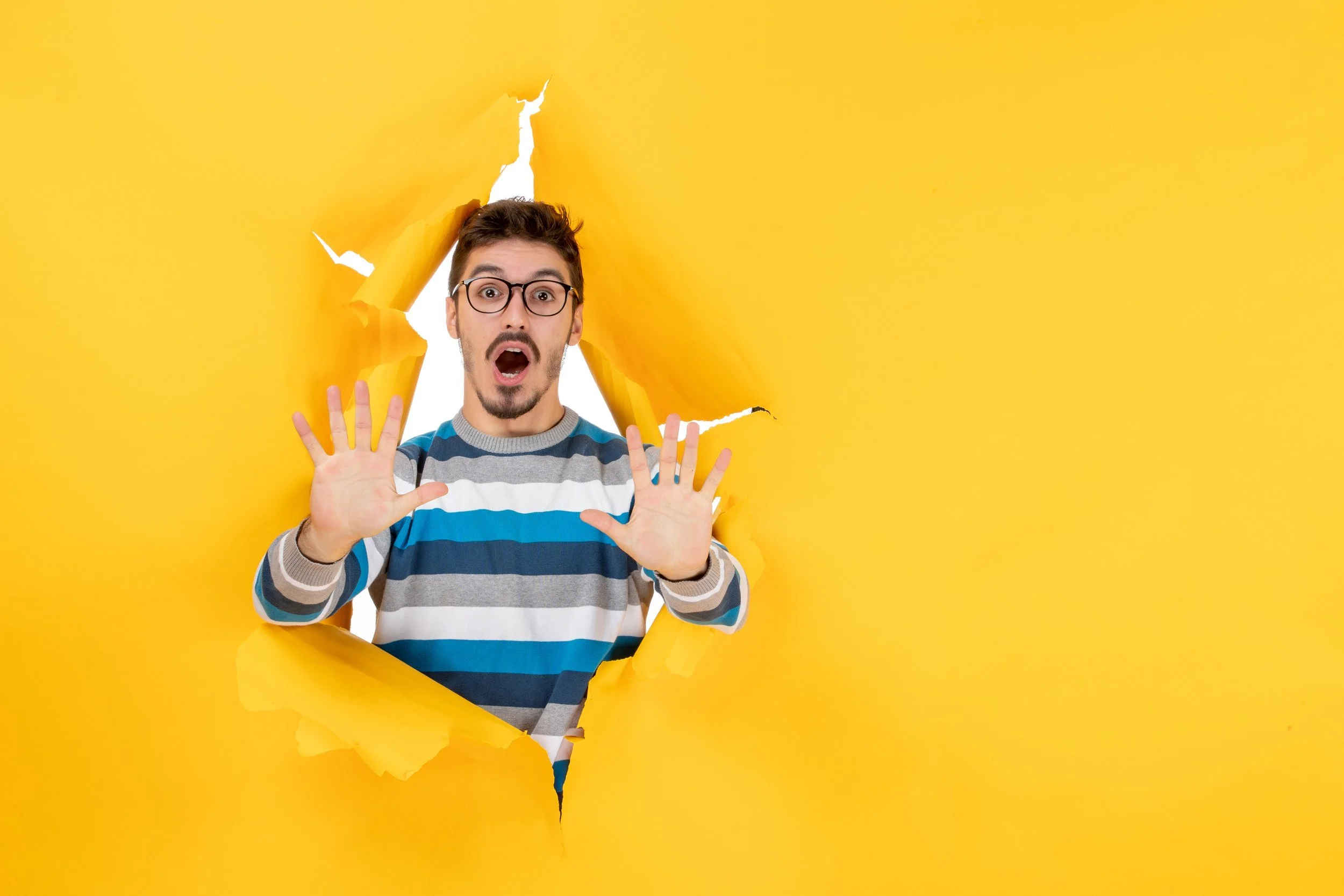Man breaking through yellow paper looking shocked