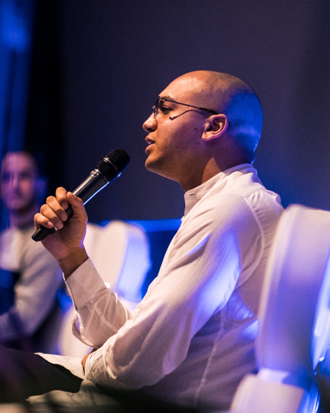 Modern home office setup with a monitor, ergonomic chair, keyboard, and indoor plants near a window with blinds.