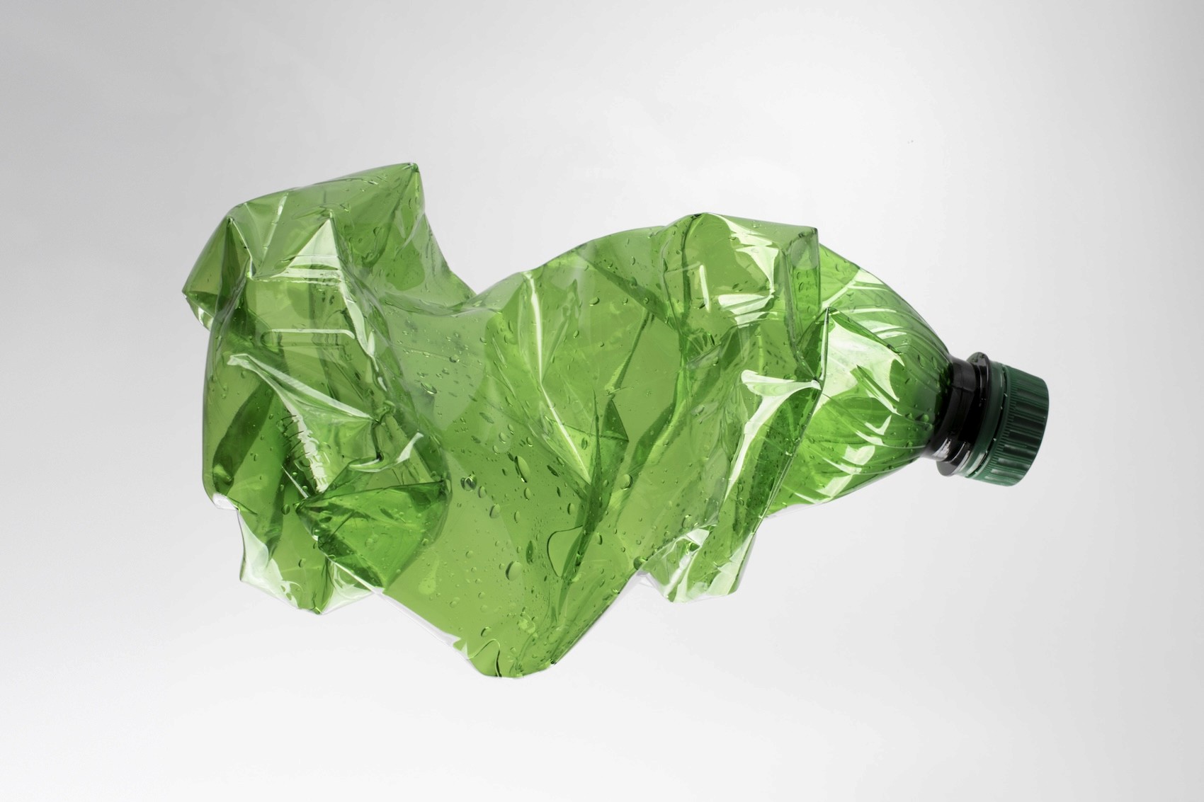 crushed green plastic bottle on a white background