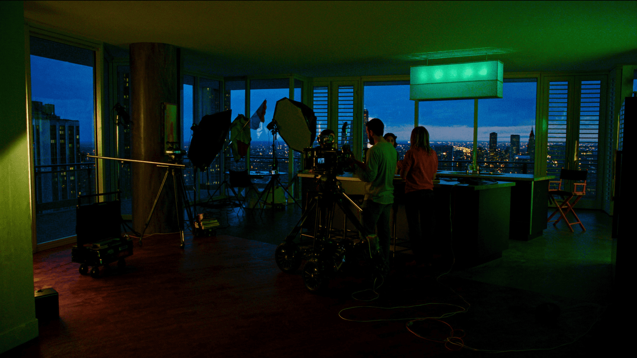 Film production crew setting up a shot inside a luxury Chicago penthouse at blue hour