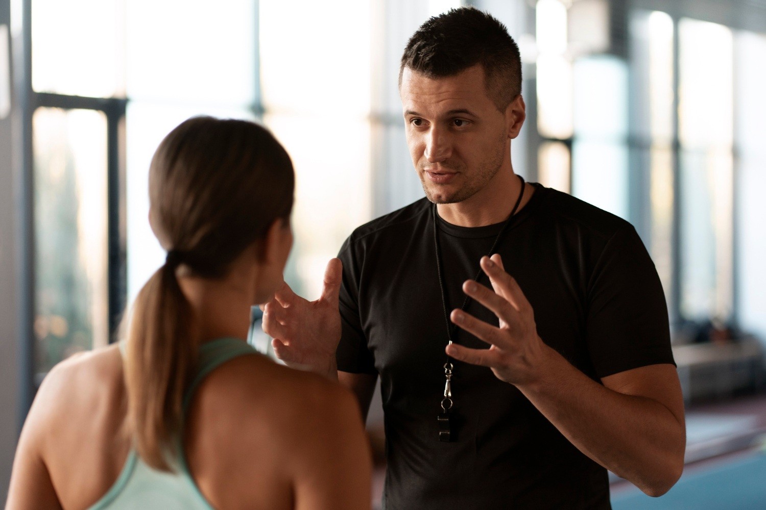 Trener rozmawiający z zawodniczką podczas treningu — symbol relacji i emocji w pracy trenera