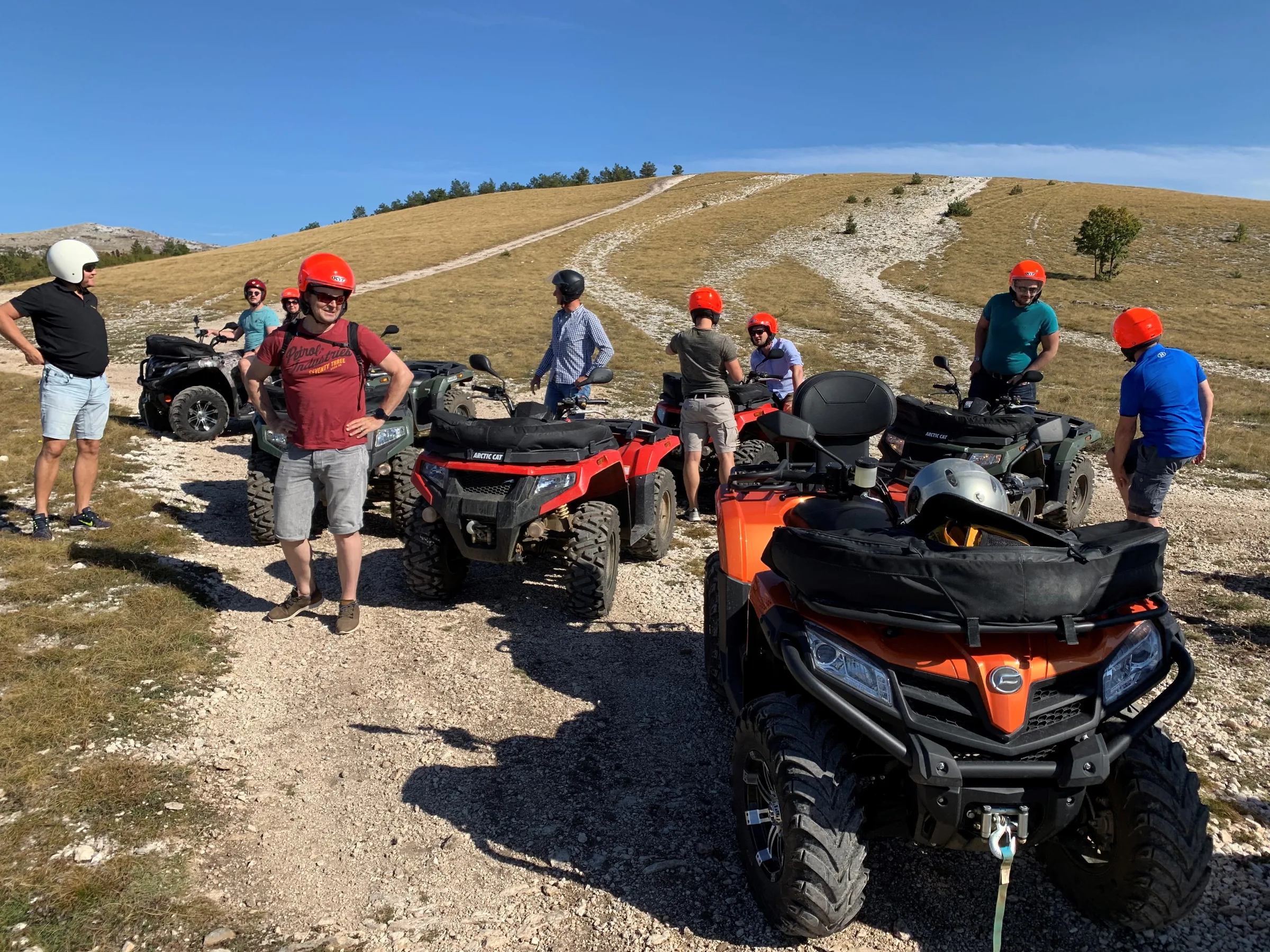 Quads fahren in einer Staubwolke über eine Schotterpiste in weiter Berglandschaft