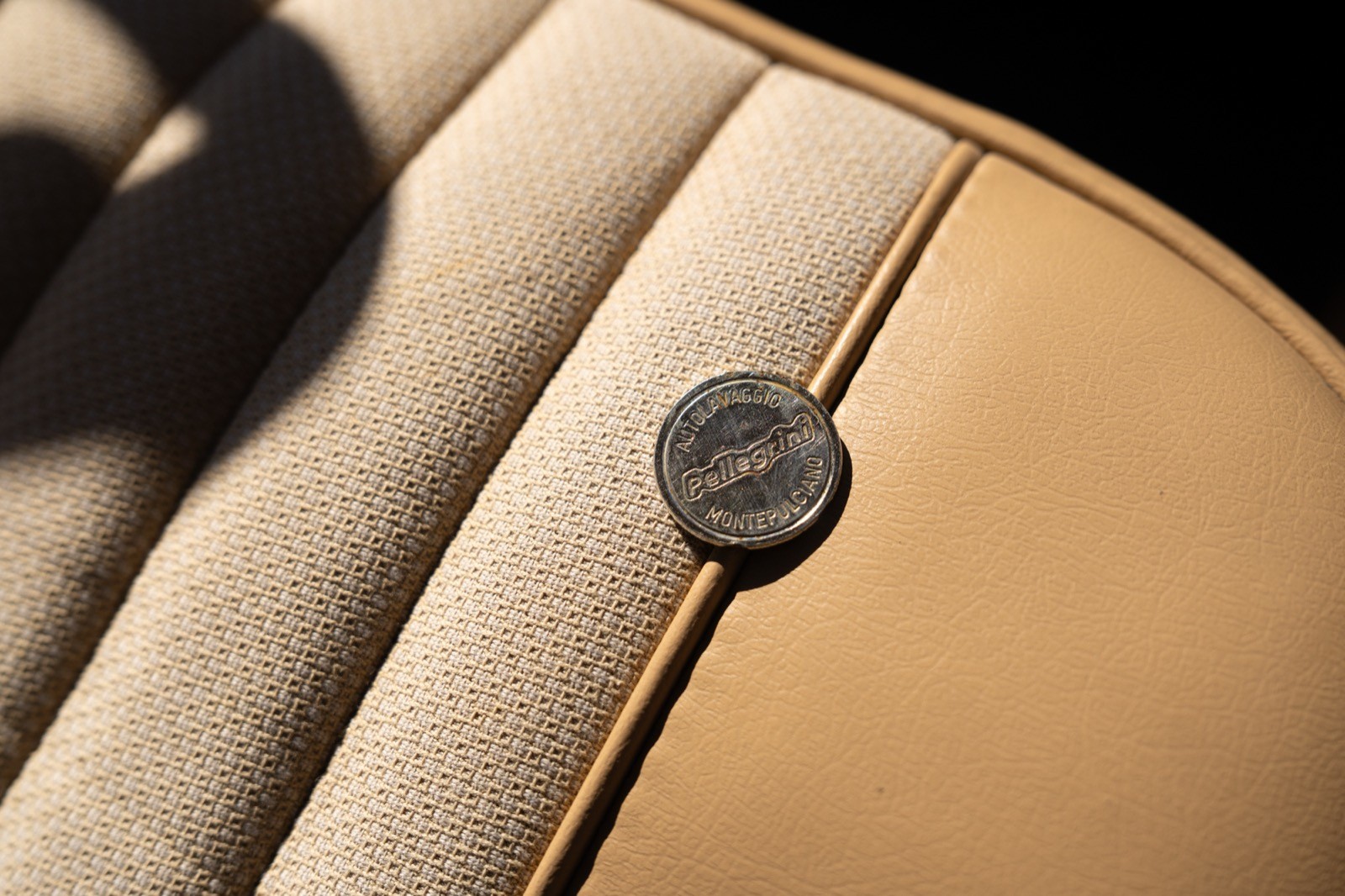 Close-up of a beige upholstered surface with a round button detail, highlighting the texture and craftsmanship.