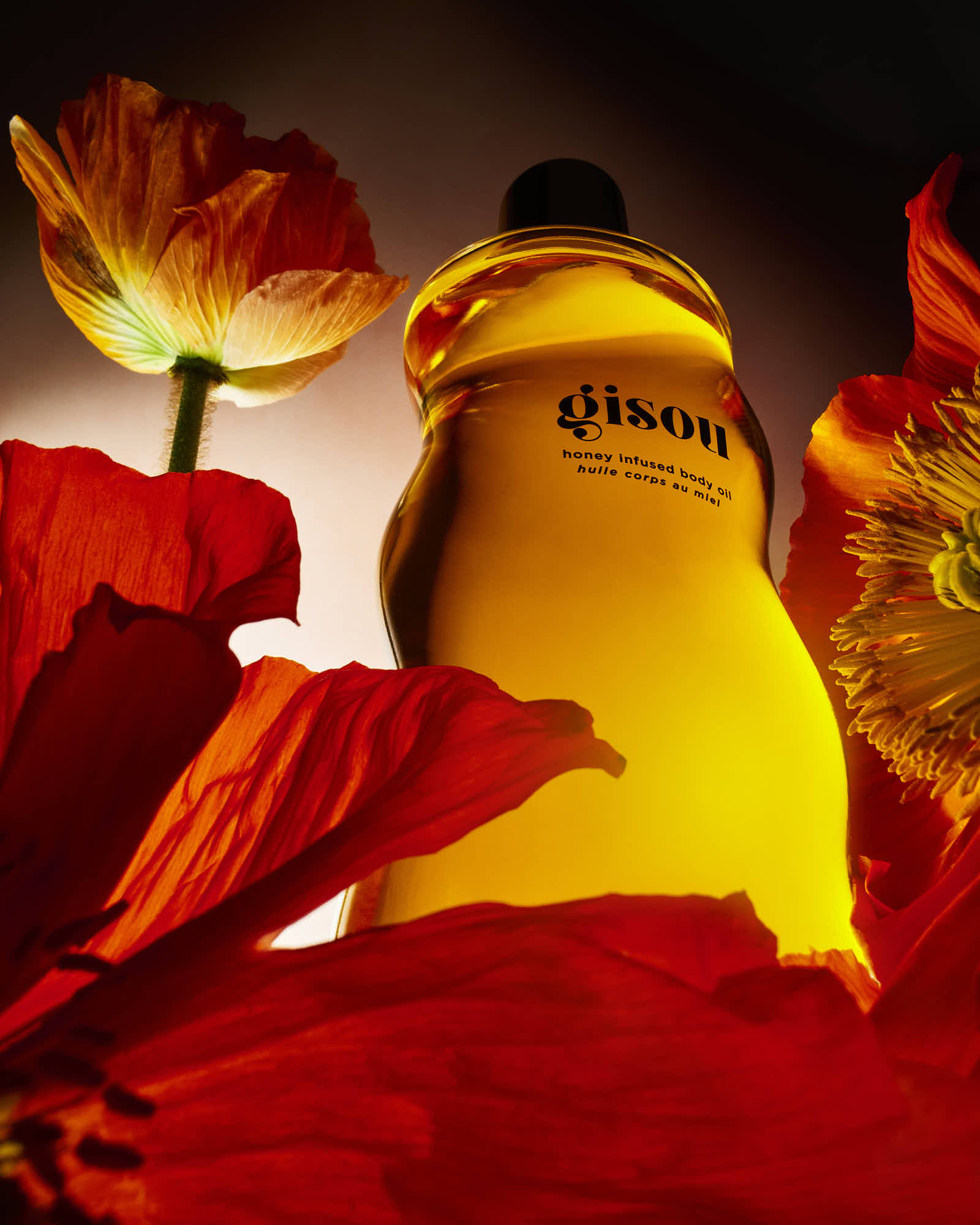 Gisou honey-infused body oil with vibrant red flowers.
