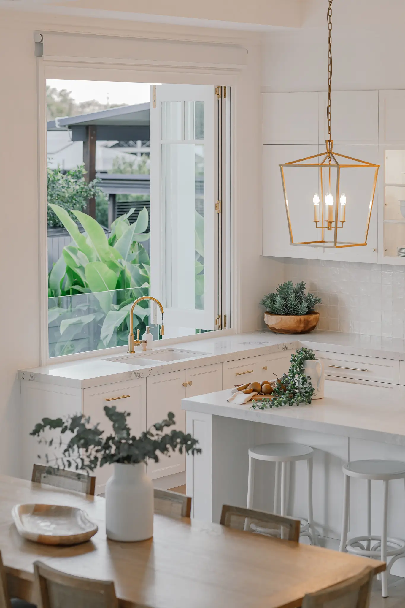 An entertainers kitchen and dining room with gold accents and custom designed built in joinery