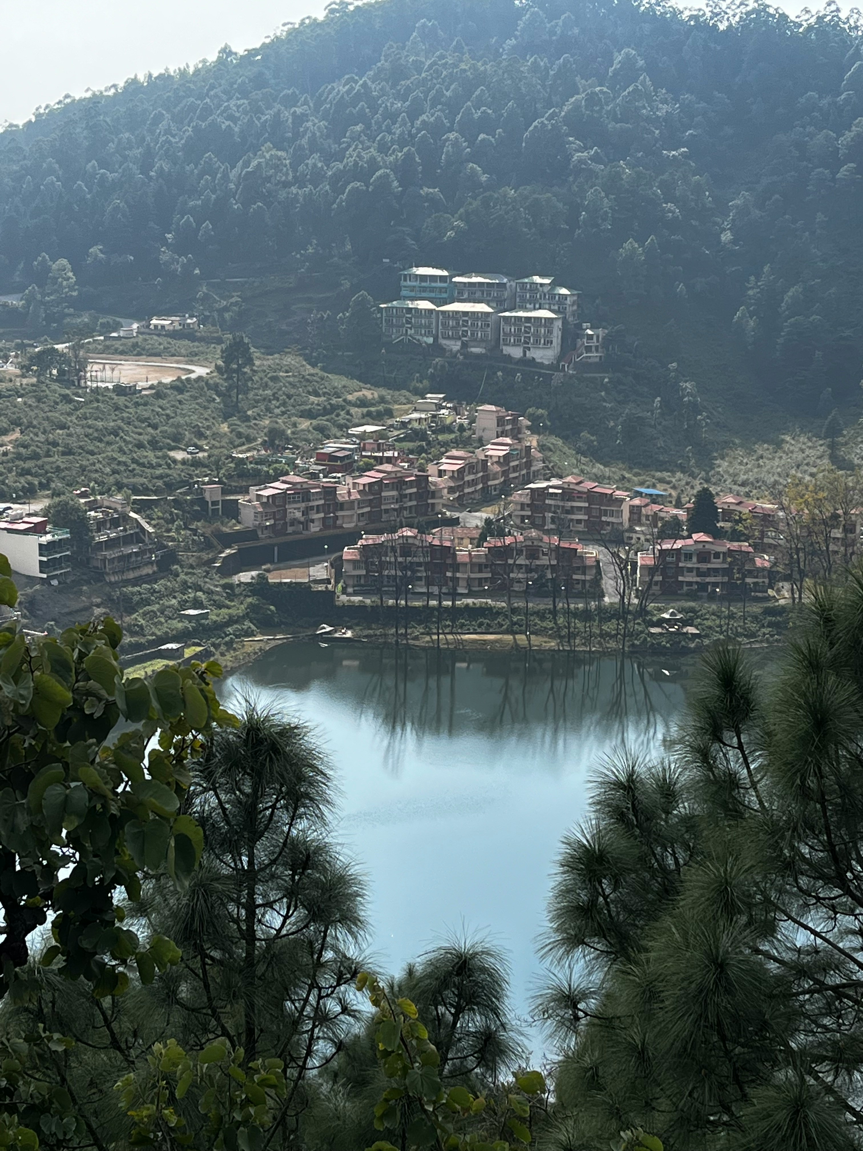 a lake surrounded by trees and buildings in the background