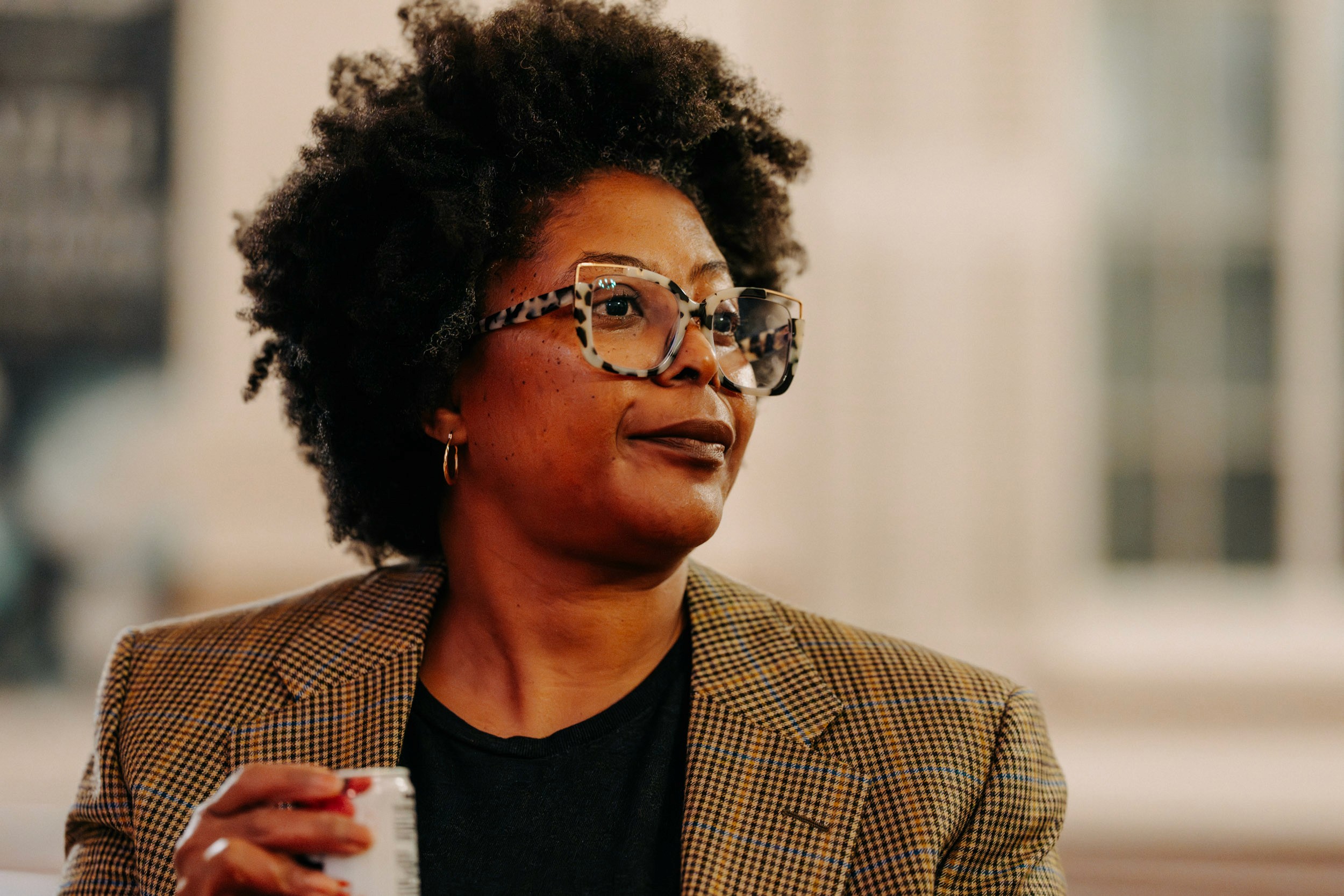 Attendee holding a drink and watching a performance at Queer Open Mic hosted by be; community in Bridgewater, Massachusetts