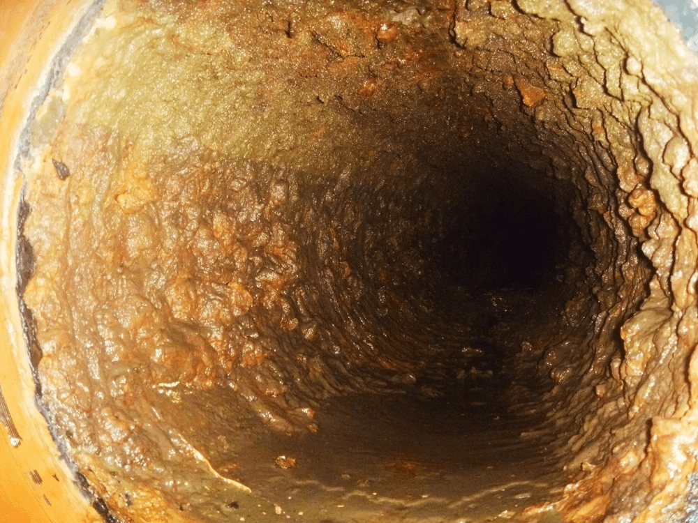 Inside a corroded, heavily fouled industrial duct before cleaning