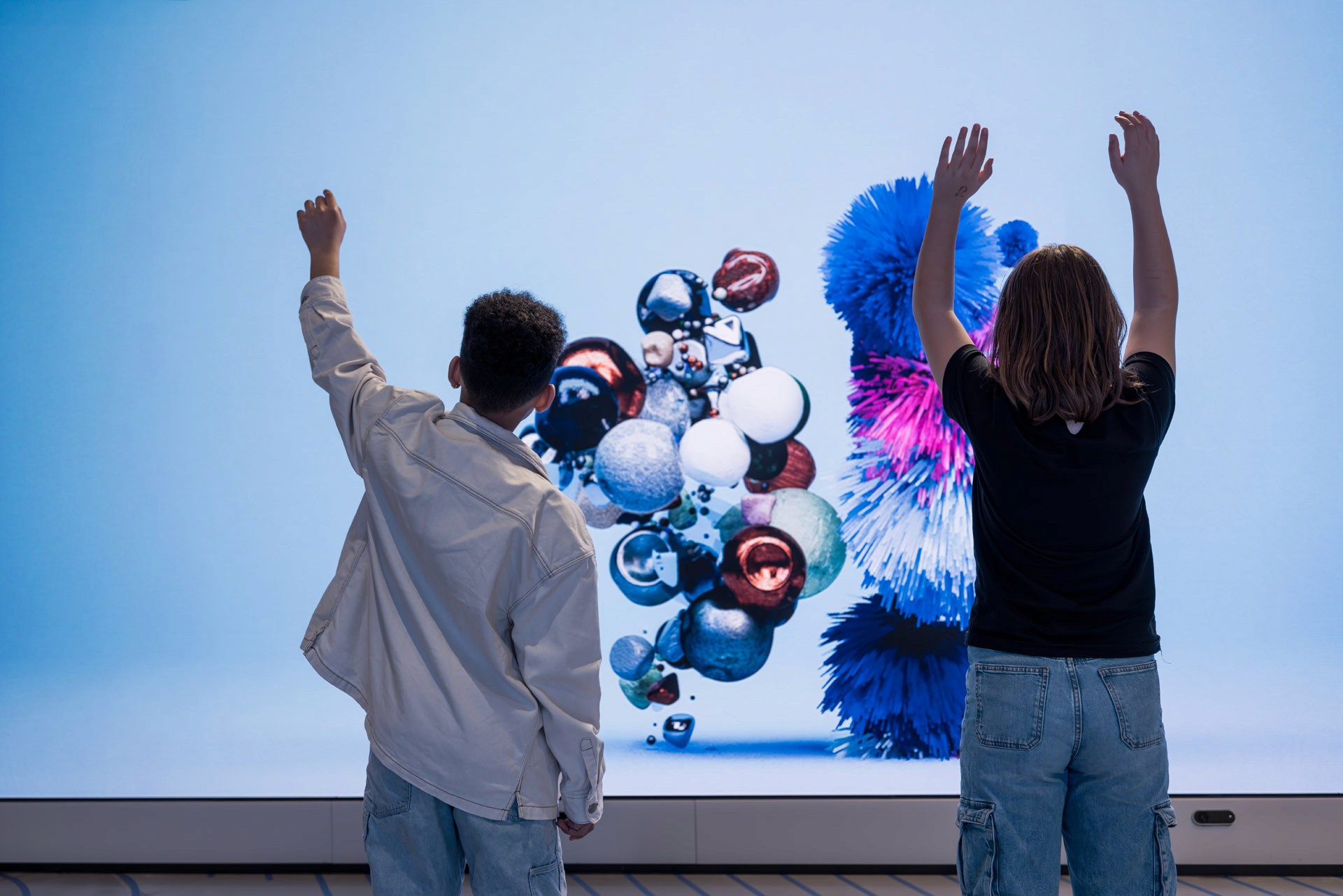 Two children cheering in front of digital art
