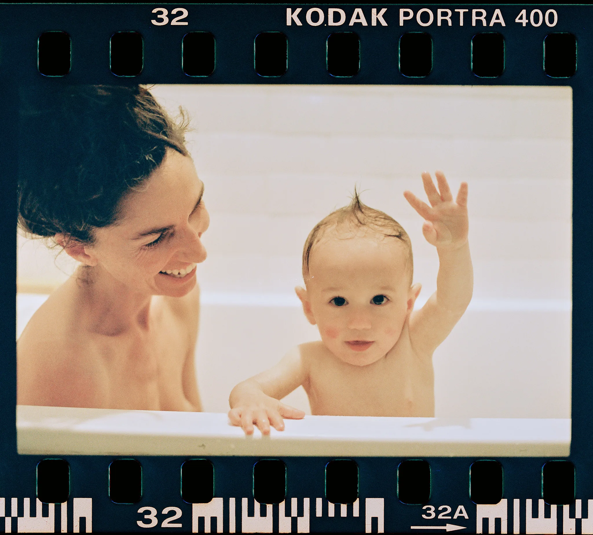baby raises hand at bathtub edge — portrait photography by Tom Kubik