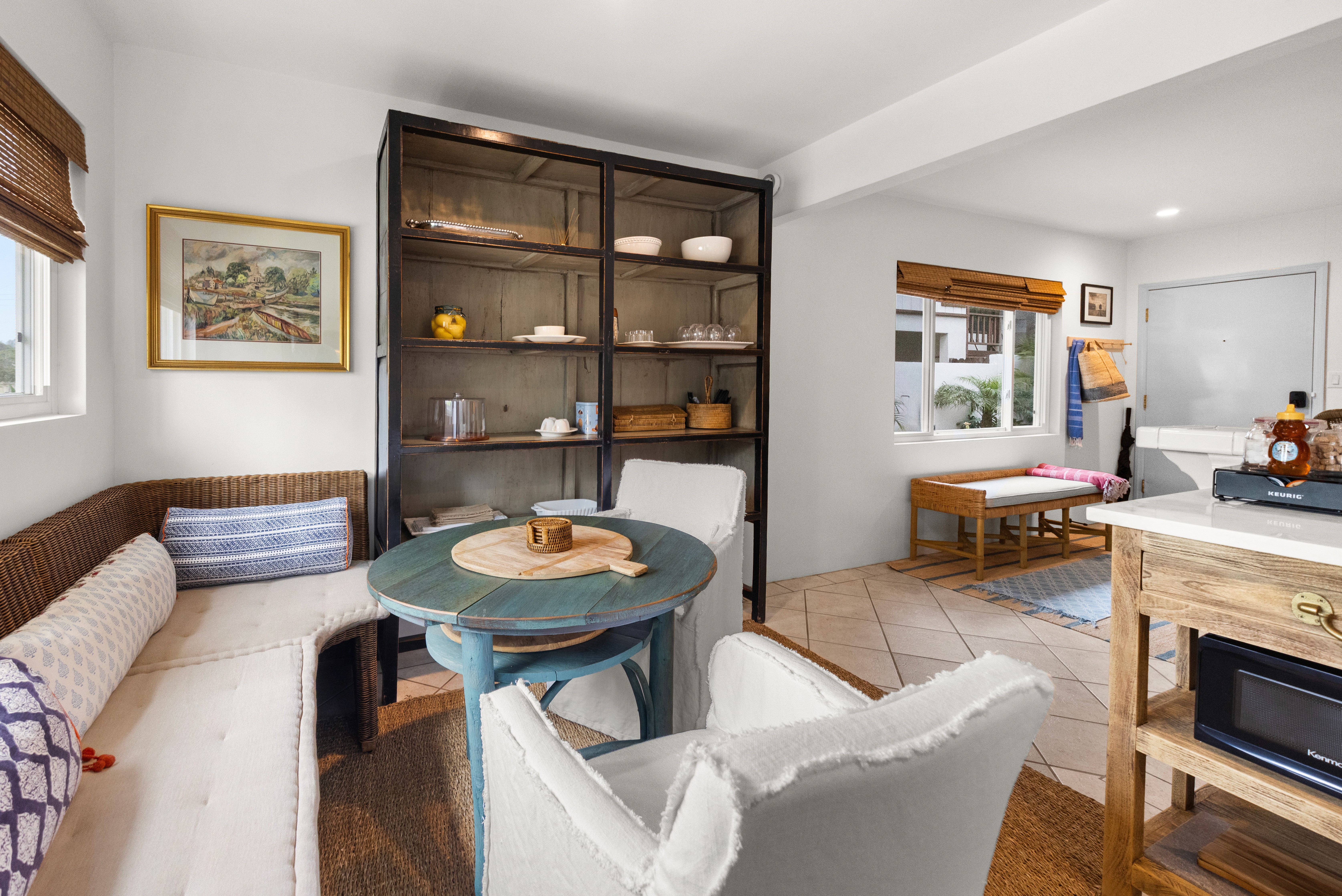 A cozy dining nook with woven seating, open shelving, and warm coastal textures—perfect for relaxed meals at home.