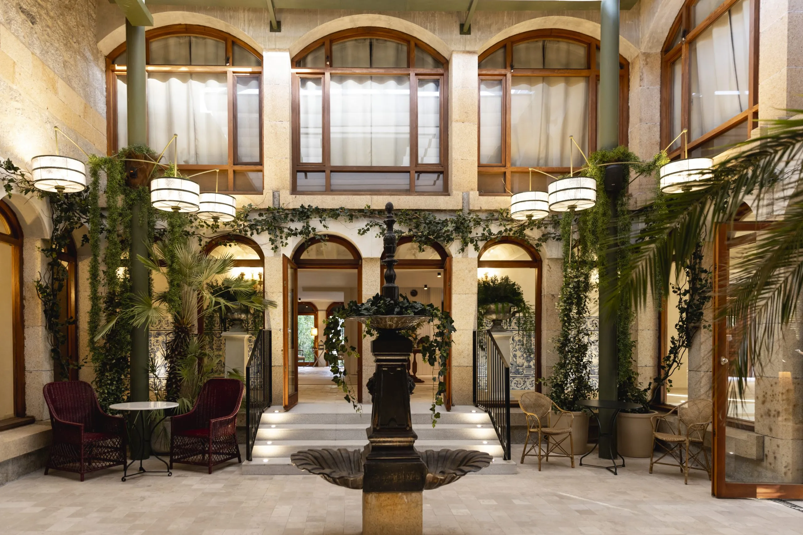 Outdoor restaurant terrace overlooking a tranquil lake at sunset. White tables and chairs are set with glassware. Sheer curtains add elegance. Calm ambiance.