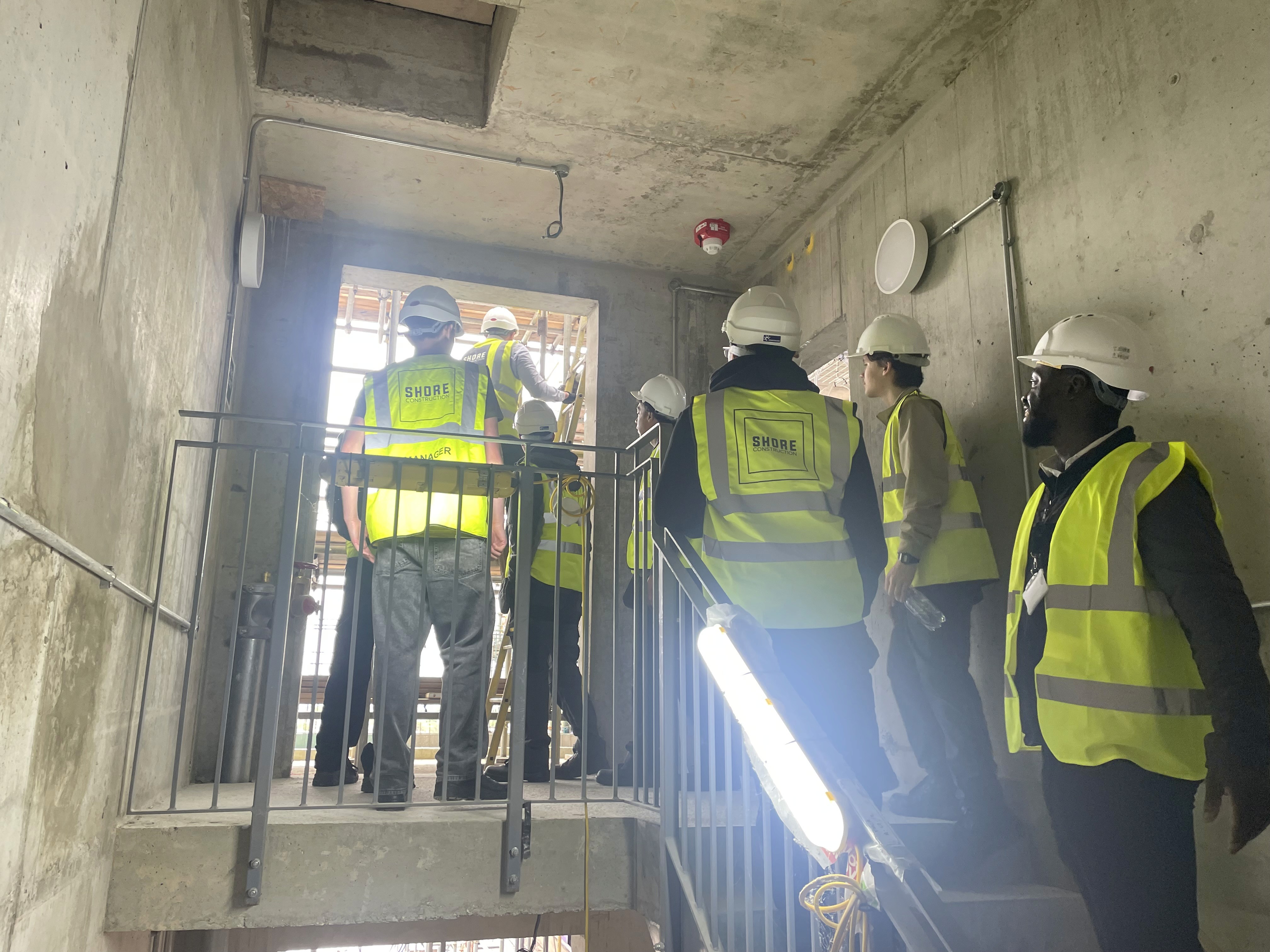 Construction engineers conducting a building site inspection inside an unfinished commercial building to ensure structural quality and safety compliance.