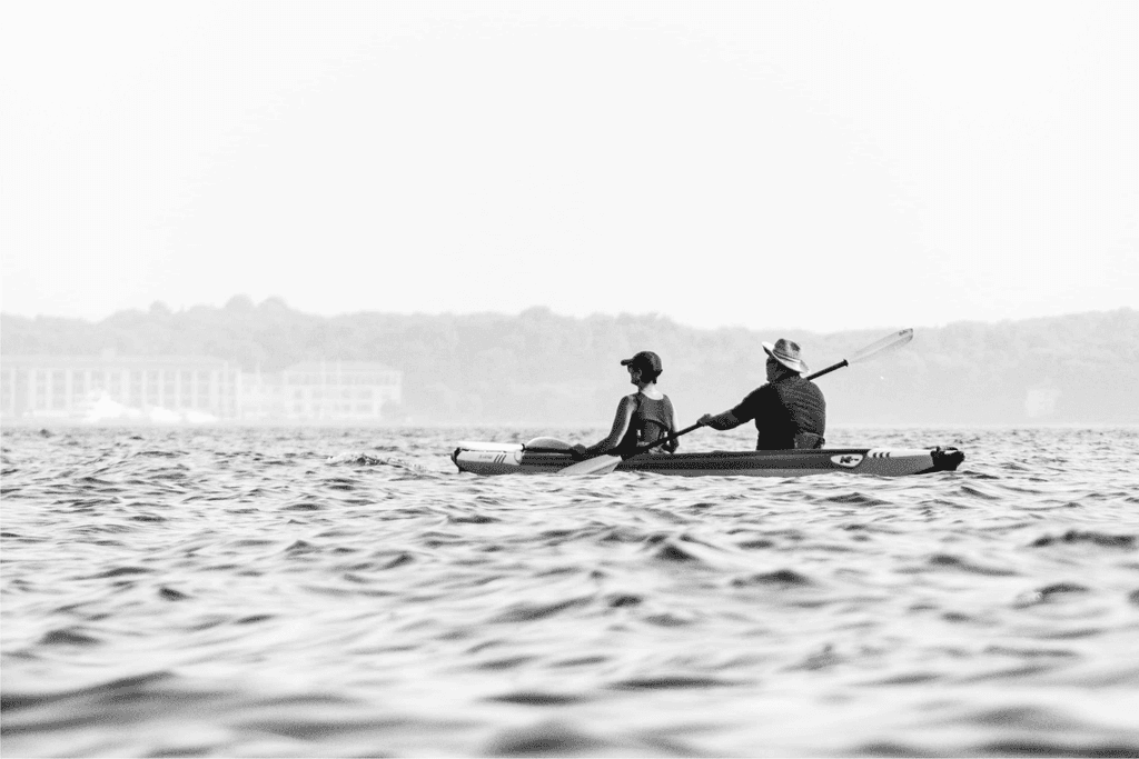 Middle-aged couple kayaking in a large body of water in a warm weather