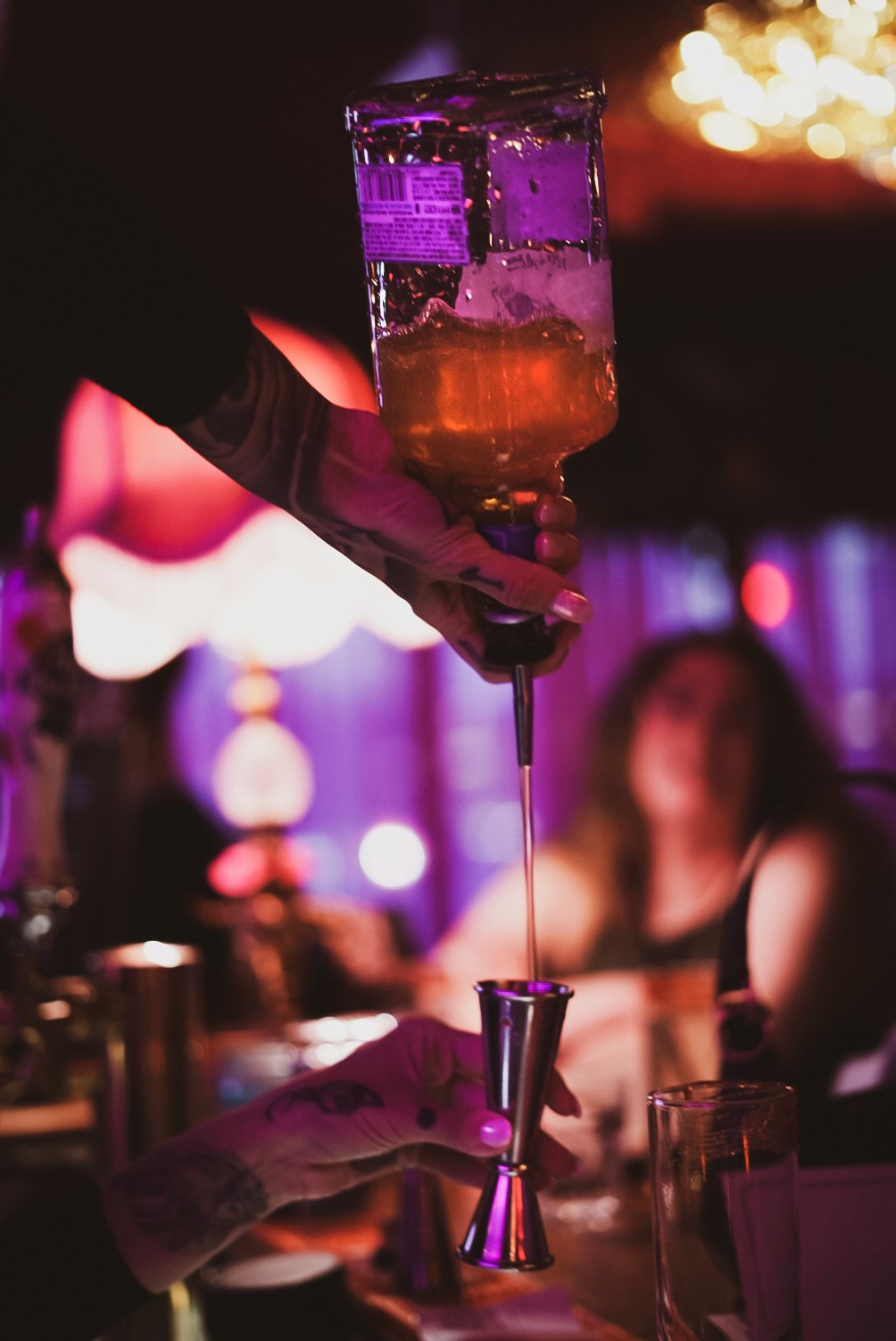woman pouring drink bottle jigger