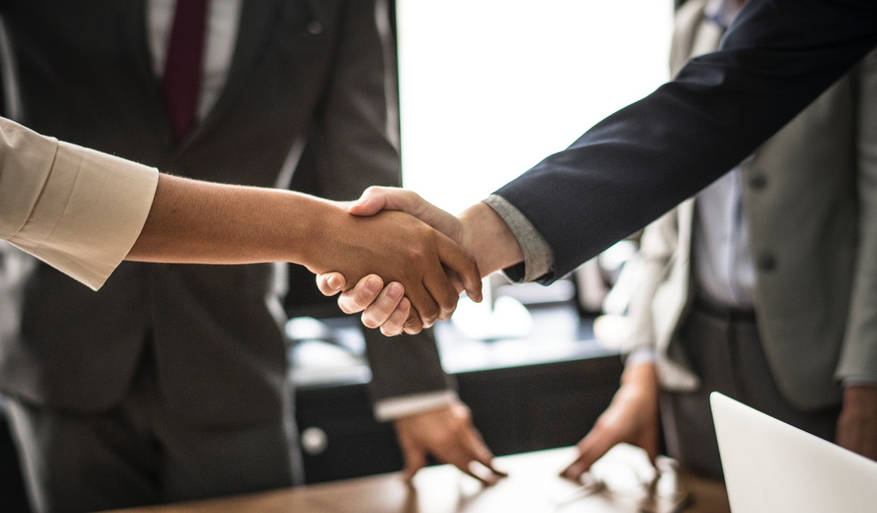 A handshake between two professionals, representing a successful partnership that aligns the priorities of landlords and tenants for long-term real estate decarbonization.