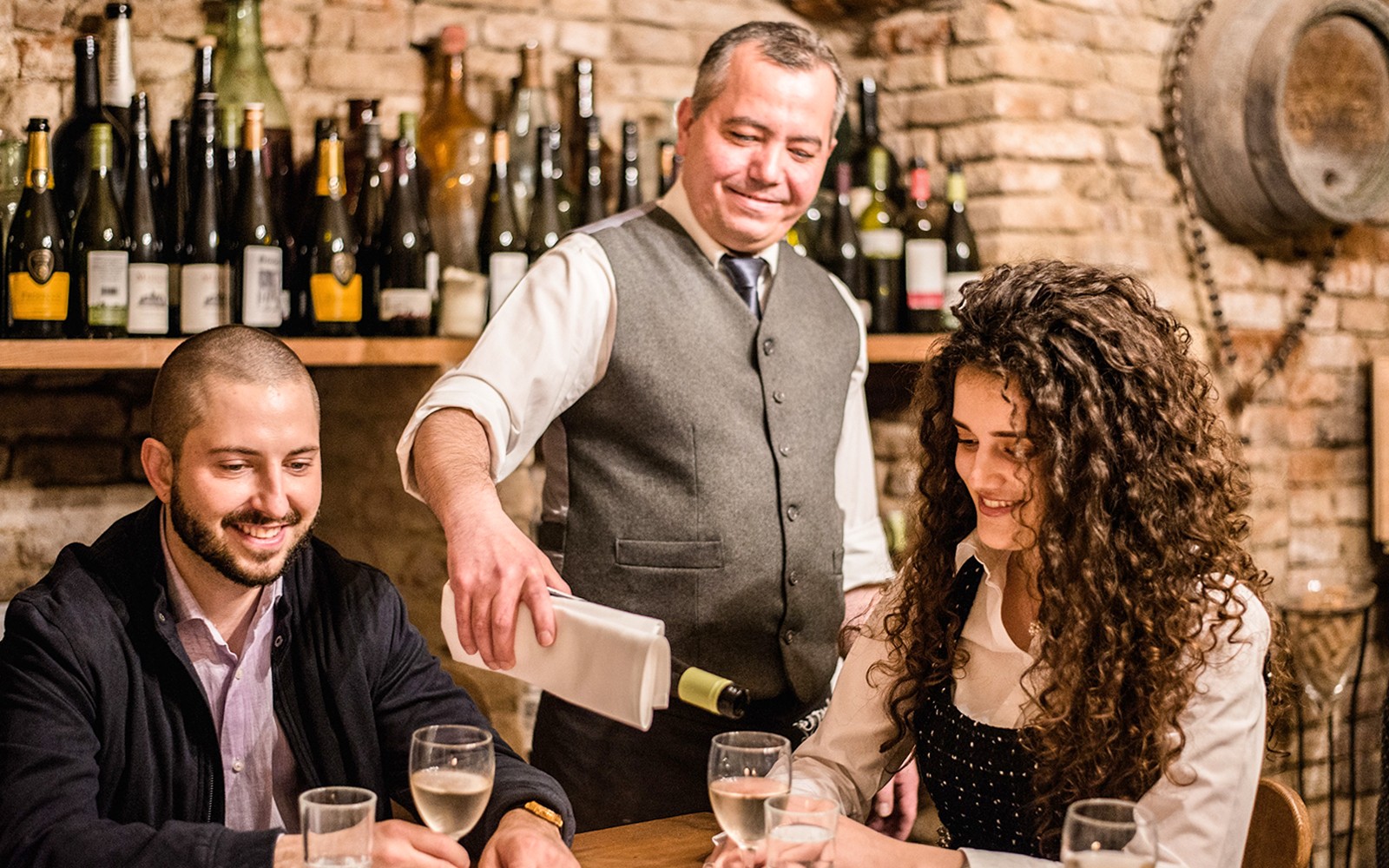 Ein Kellner schenkt Wein für Gäste in einer privaten Weinkellerei-Verkostung ein.
