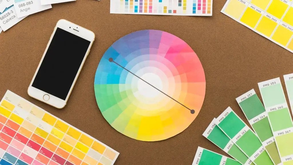 a circular paper with a color wheel hue and shade and a phone on a table, Choose the best colour palette for your brand