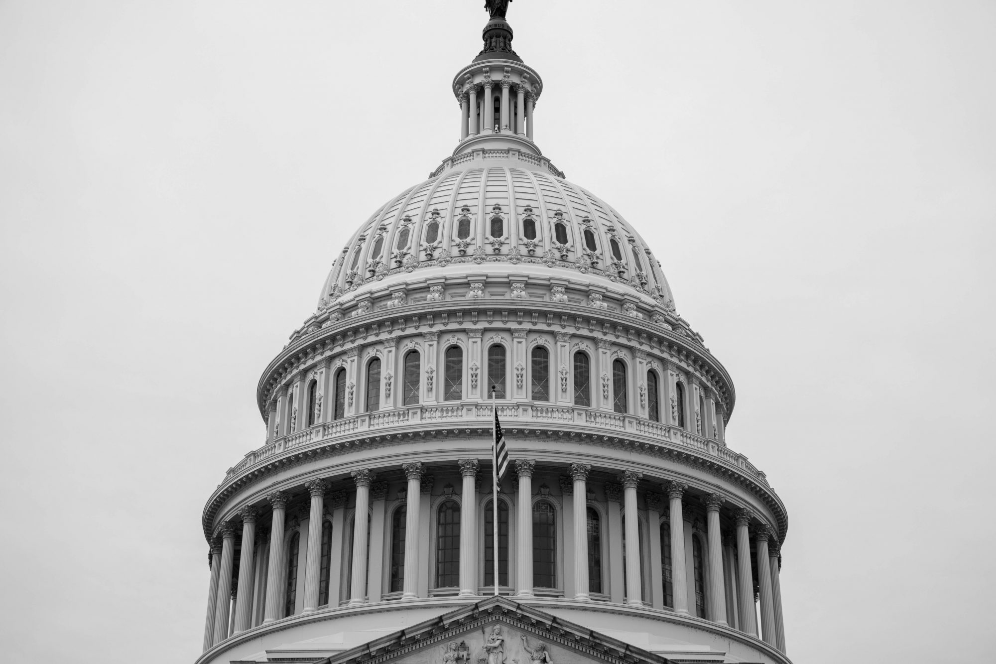 A close-up view of the dome of a historic building, featuring intricate architectural details against a gray sky.
