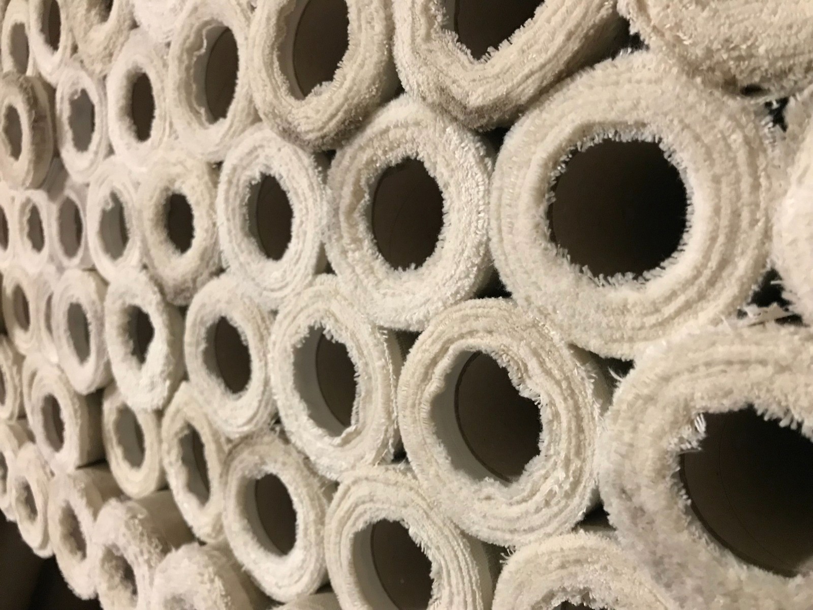 Rolls of canvas fabric seen end-on in the warehouse