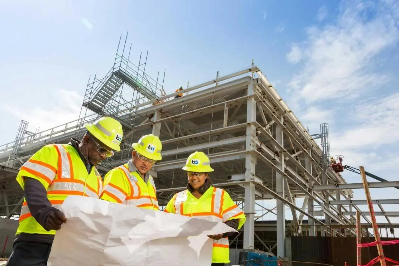 Construction site team reviewing building plans to document quality and hold subcontractors accountable