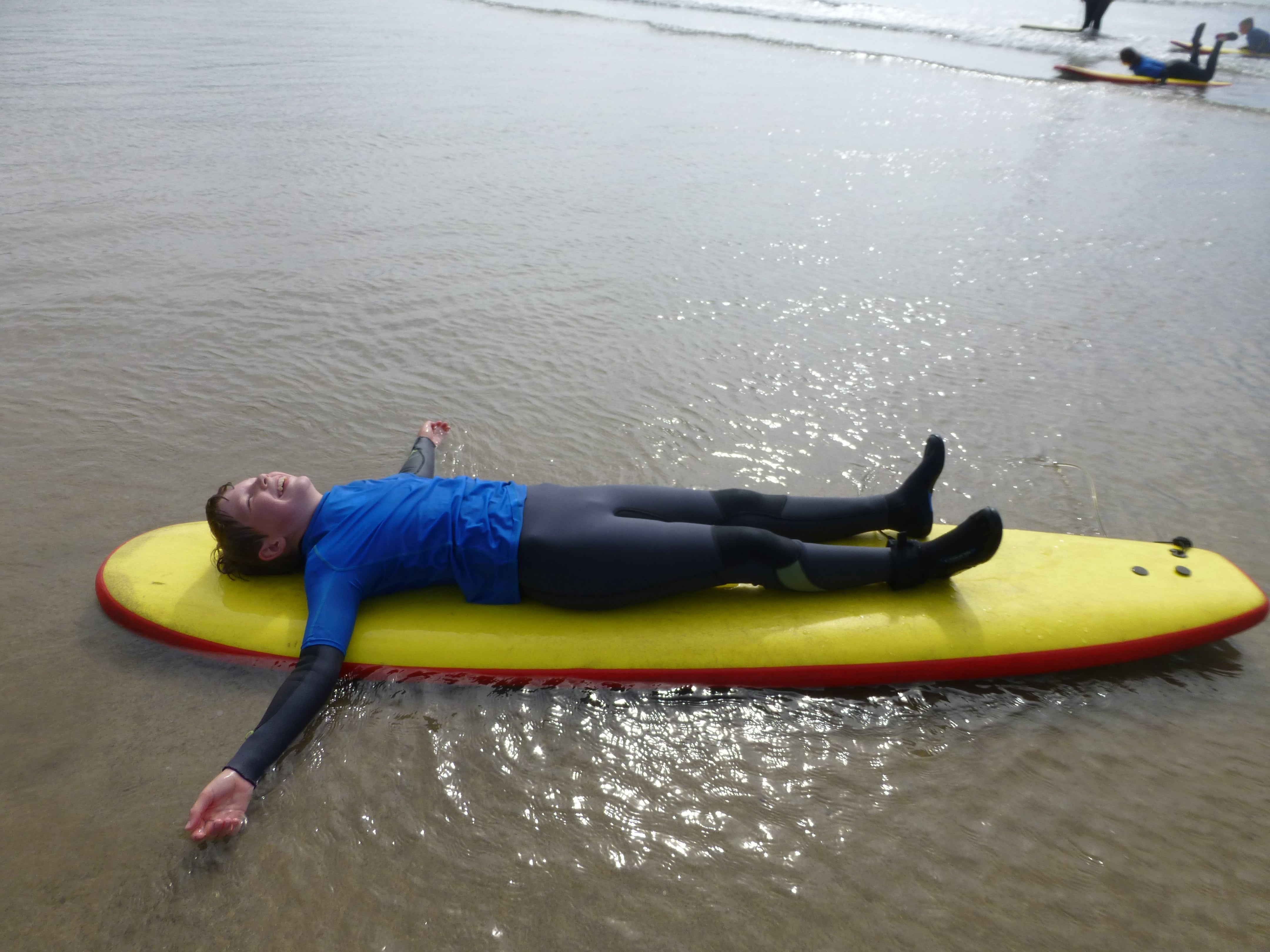 Young person laying down on surfboard in the sea