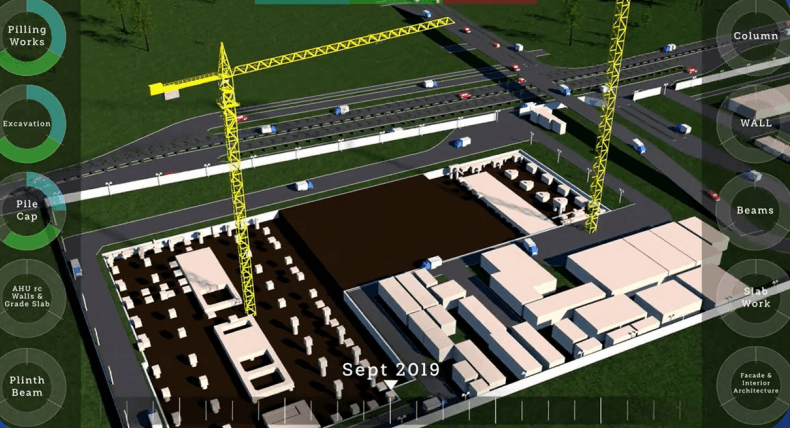 A man stands while two people sit at a table in an office setting, smiling and engaged in conversation. The mood is friendly and collaborative.