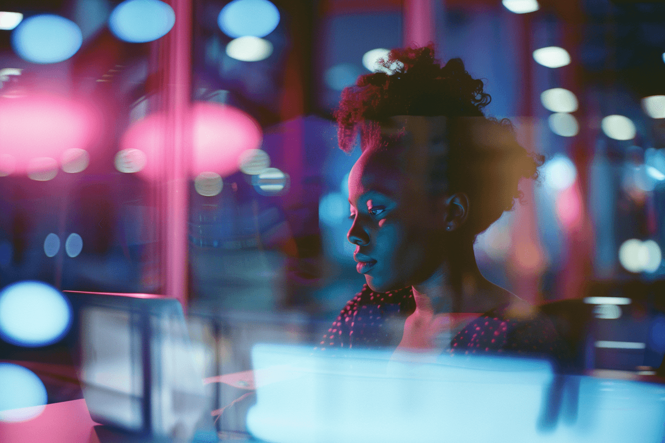Woman working at night with reflections of lights off the glass