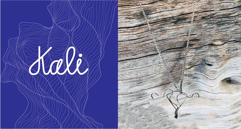 A white text logo Kali on a blue pattern background and a pendent over a piece of wood.