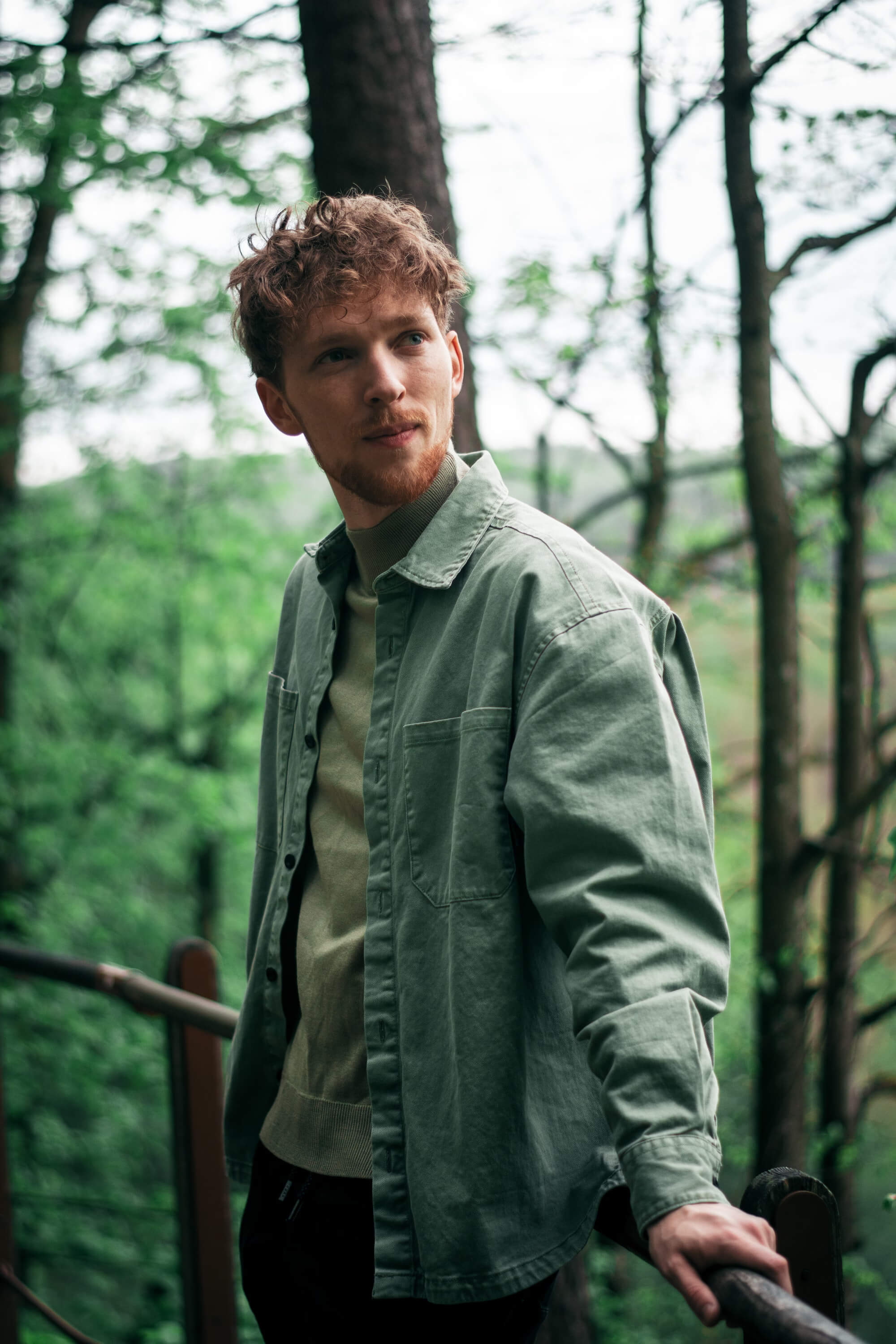 A person with shoulder-length blonde hair wearing a black newsboy cap and a black sweater.