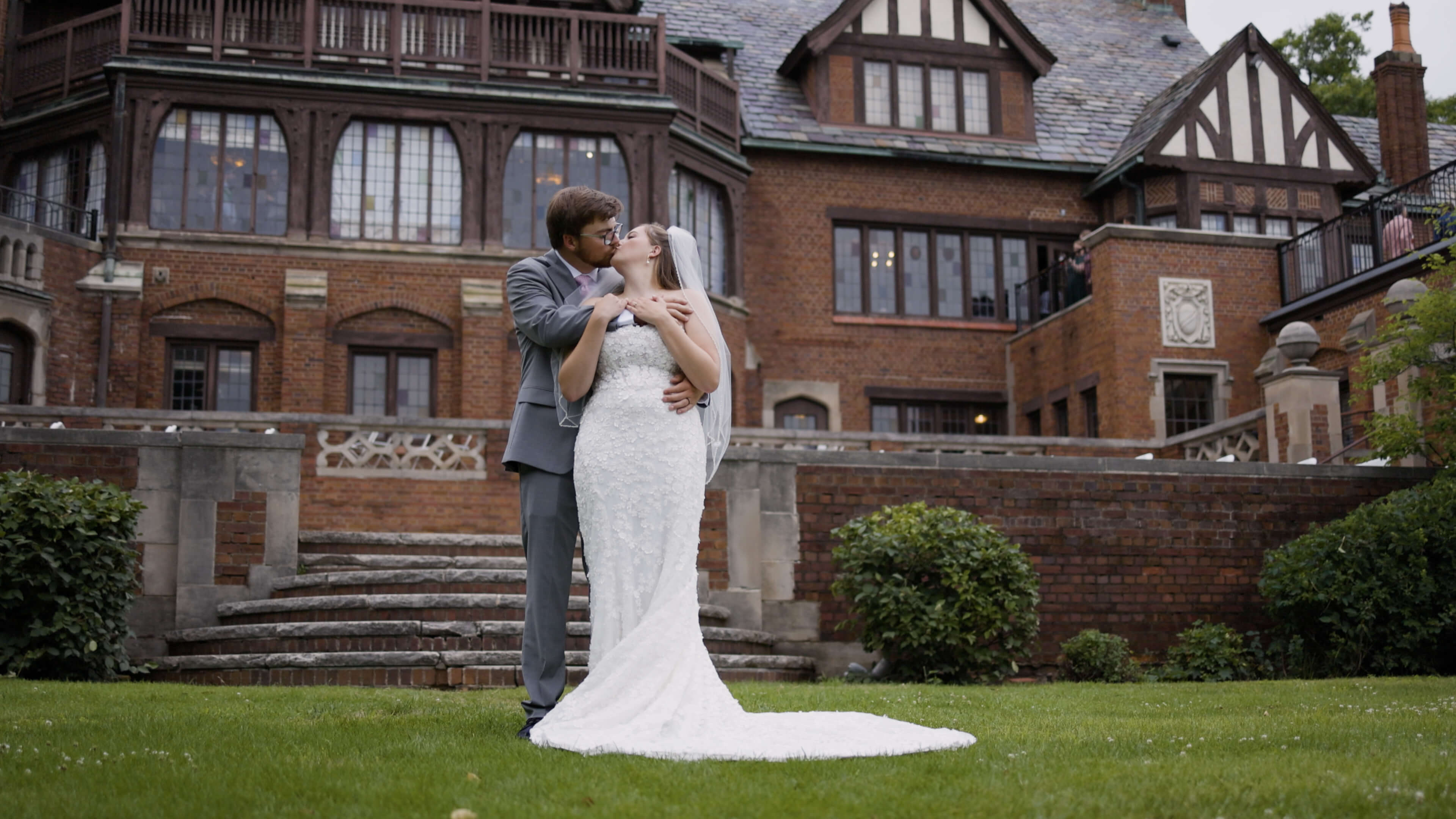 A bride and groom kissing in front of a beautiful mansion
