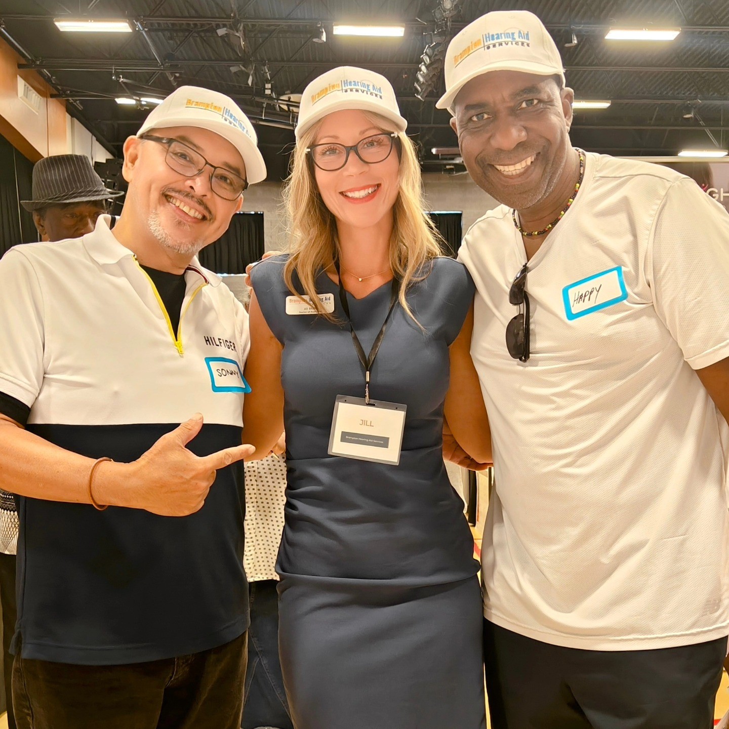 A man in a purple shirt sits across from an elderly man in a vest at a desk, engaged in conversation.