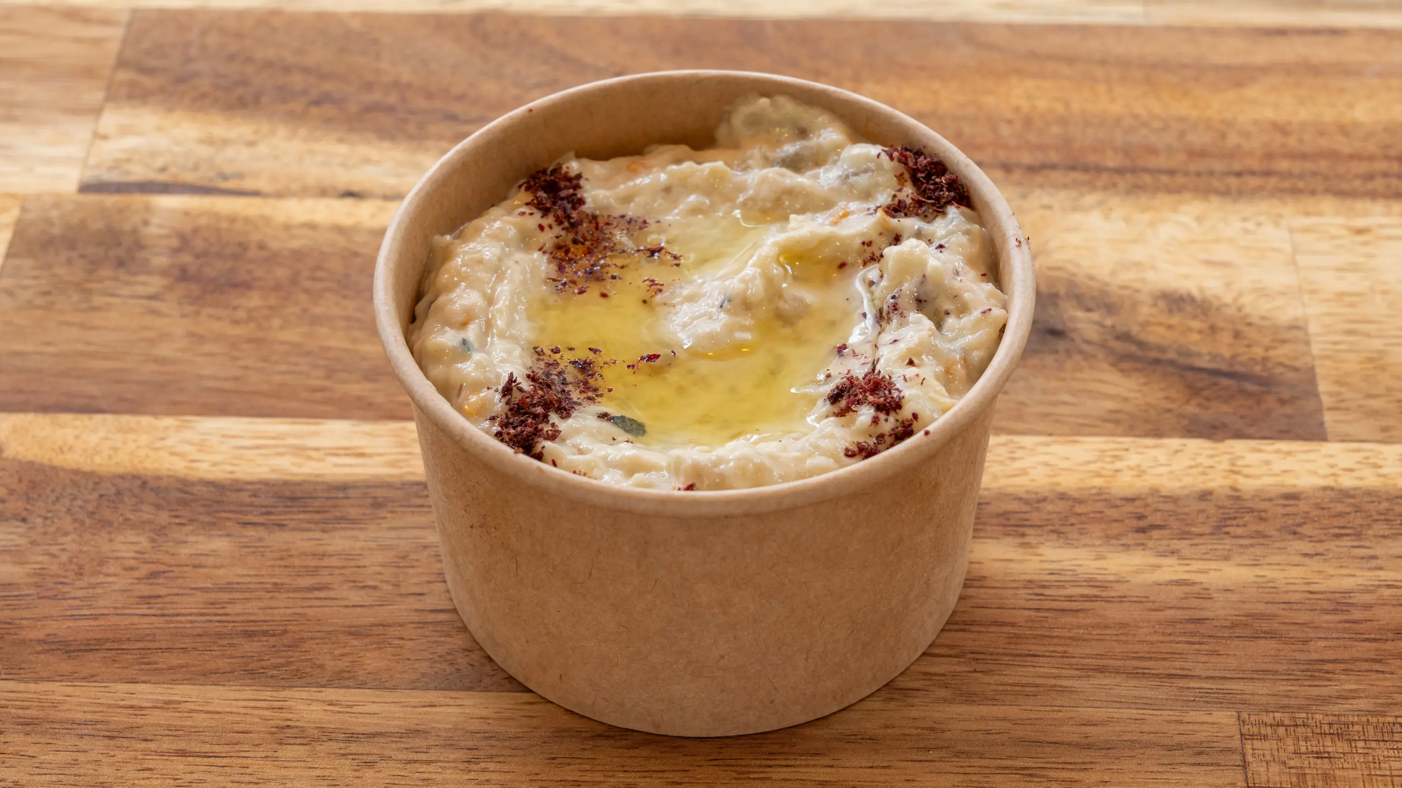 Caviar d’aubergine dans un pot kraft avec un filet d’huile d’olive et du zaatar