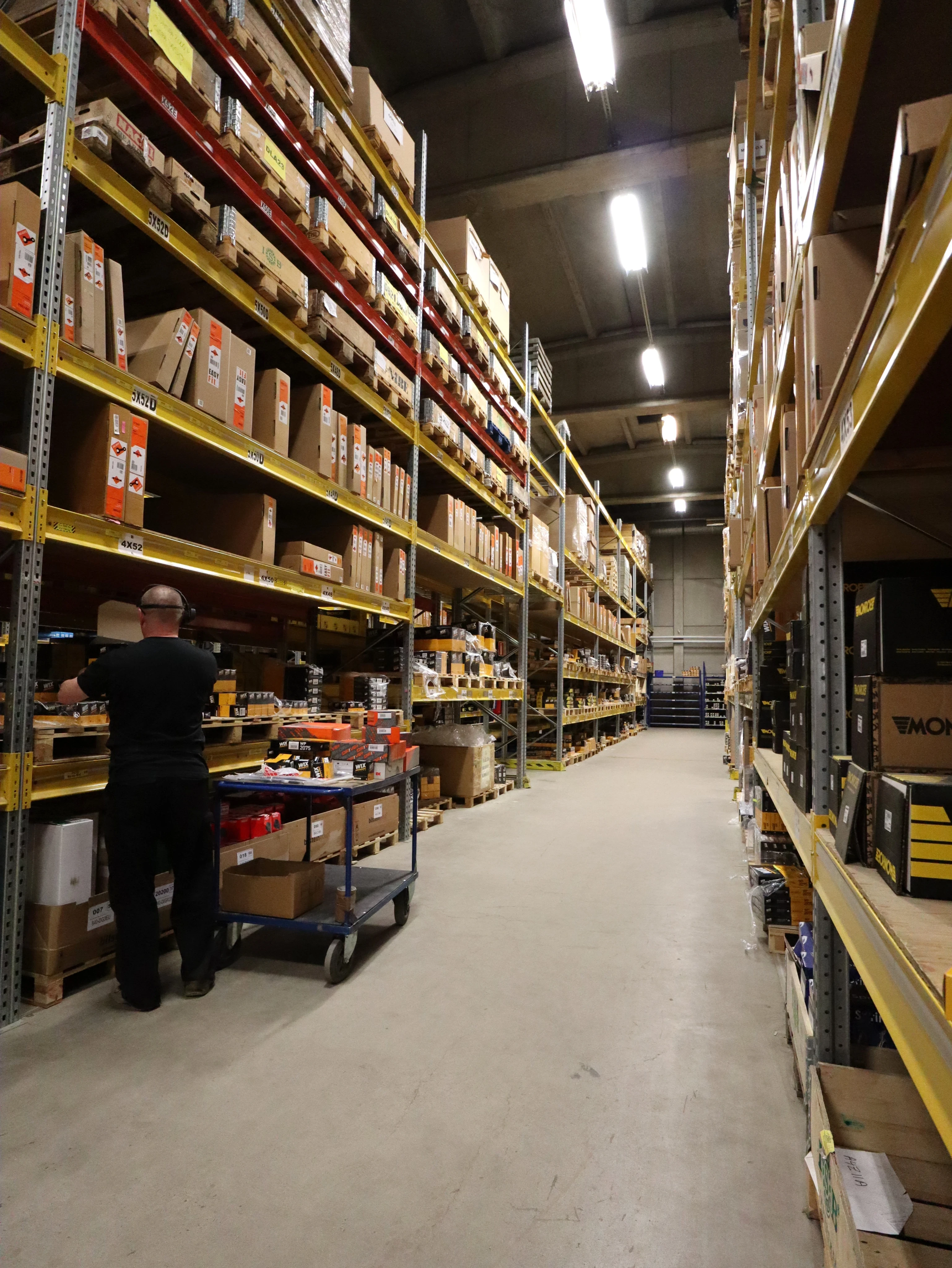 Warehouse worker organizing shelves stacked with boxes and supplies
