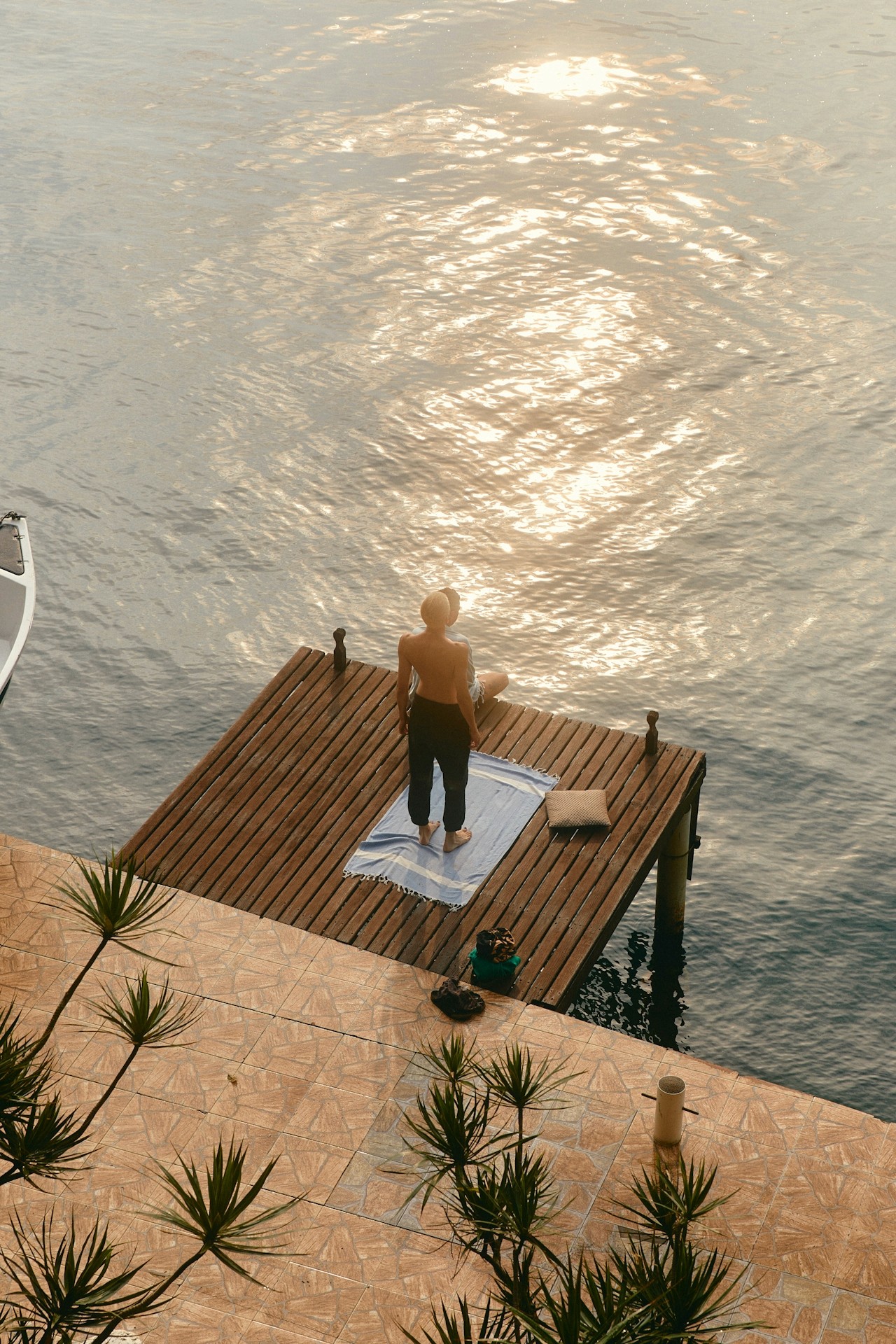 A person standing quietly on a dock overlooking calm water.