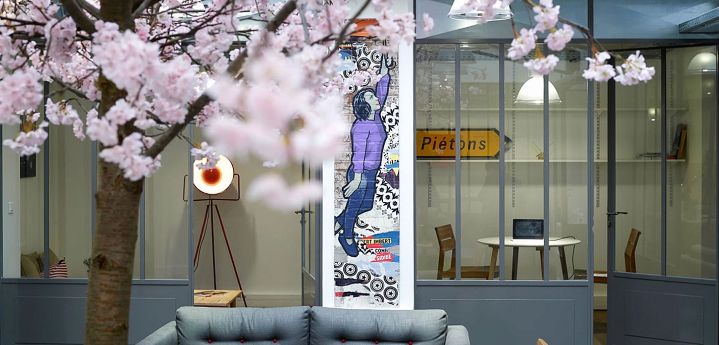 Intérieur moderne avec cerisier en fleurs, œuvre d'art, lumière sur trépied et coin bureau. Ambiance printanière et design.