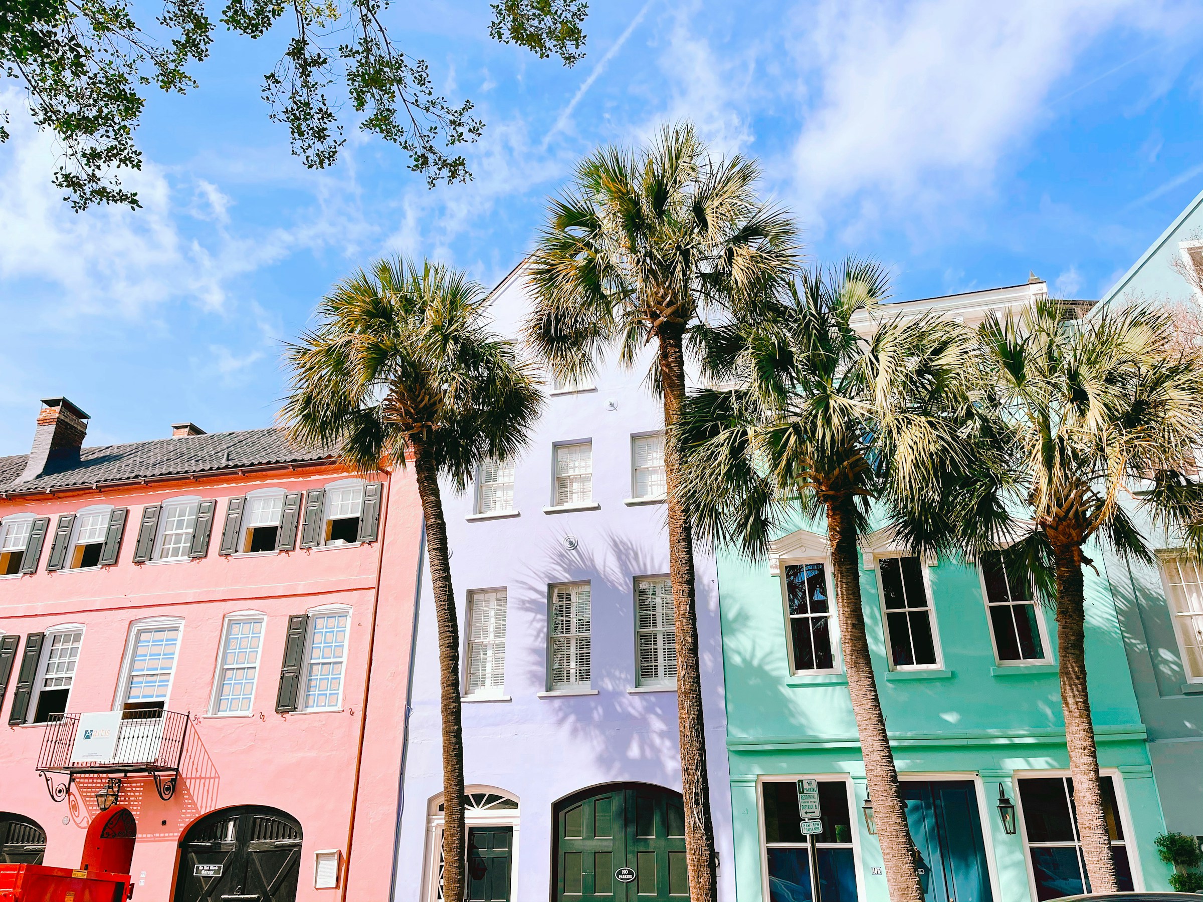 Pastel row houses and palmetto trees on a sunny Charleston street