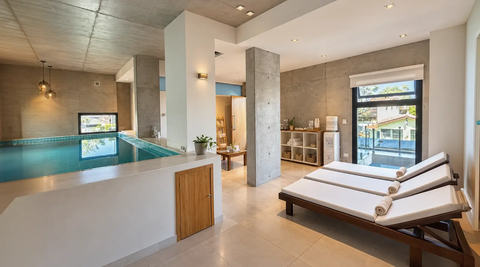 Piscina interior del spa junto a reposeras y ventanales con vista al jardín