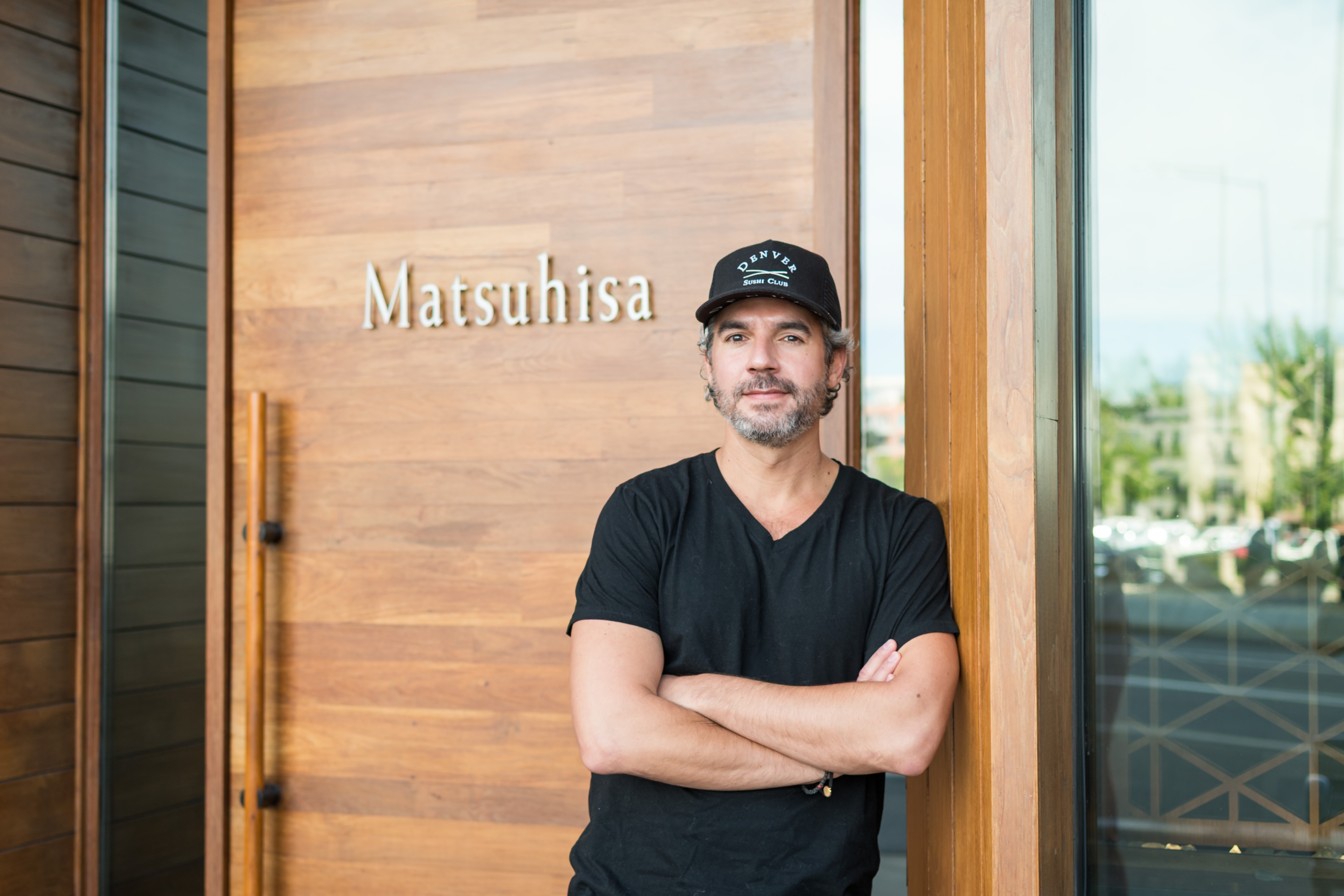Black and white image of people working at a table with laptops, showing hands gesturing during discussion of digital content displayed on screens, with fabrica® logo in the corner.