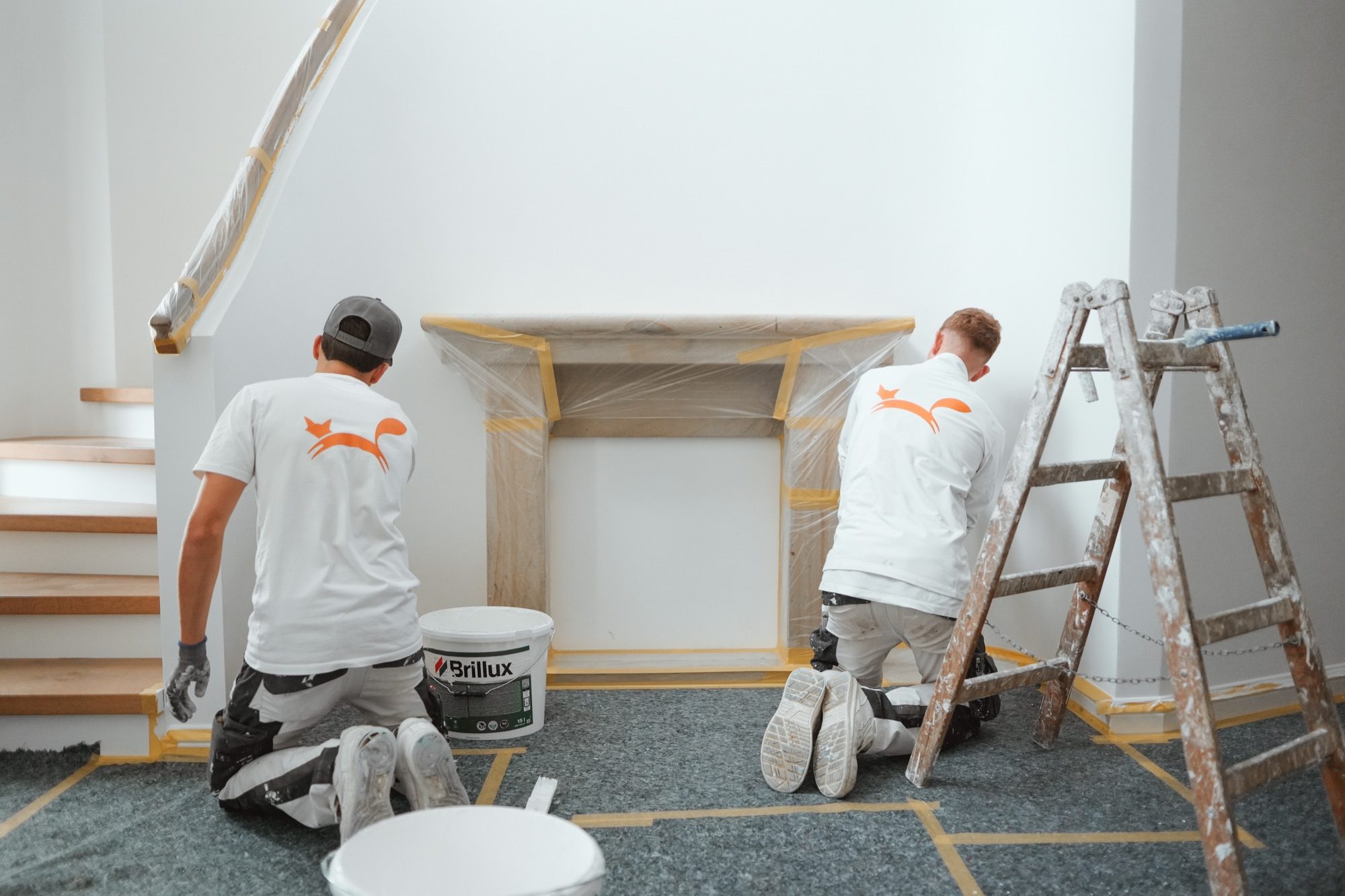 Zwei Maler arbeiten kniend an einem Kaminsims