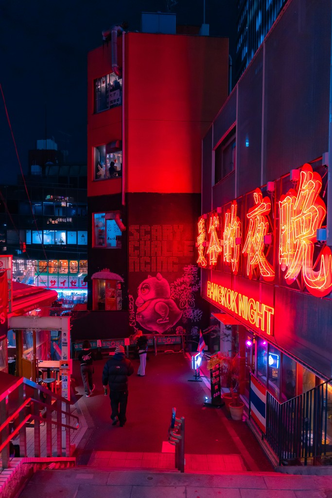 A restaraunt with neon signs at the bottom of a staircase