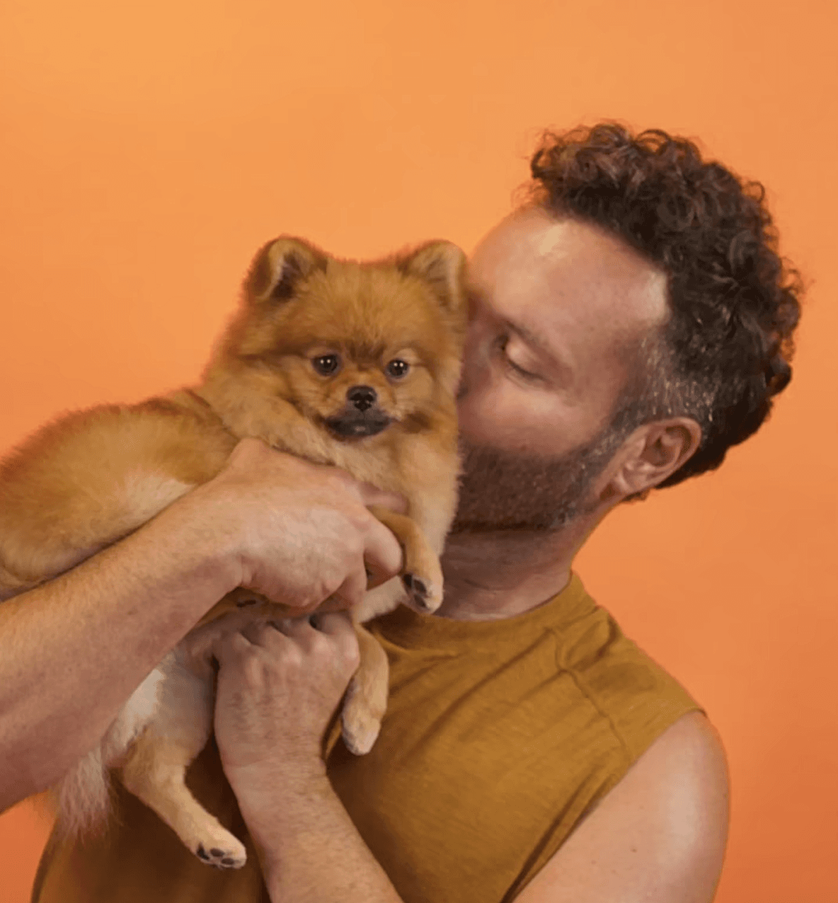 Joyful image of a man kissing his small fluffy dog to show love, trust, and personalized care.