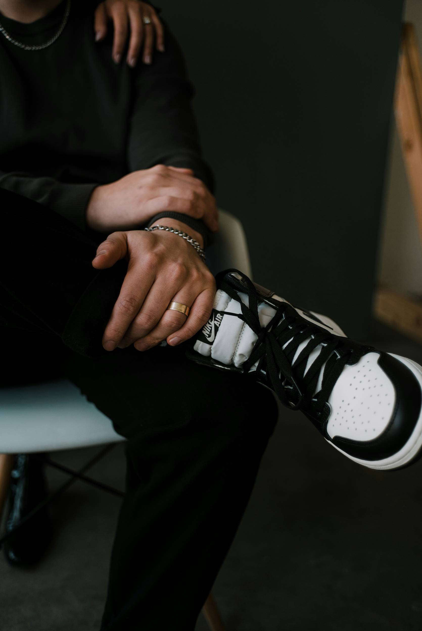 A pair of hands with jewlery resting on an ankle