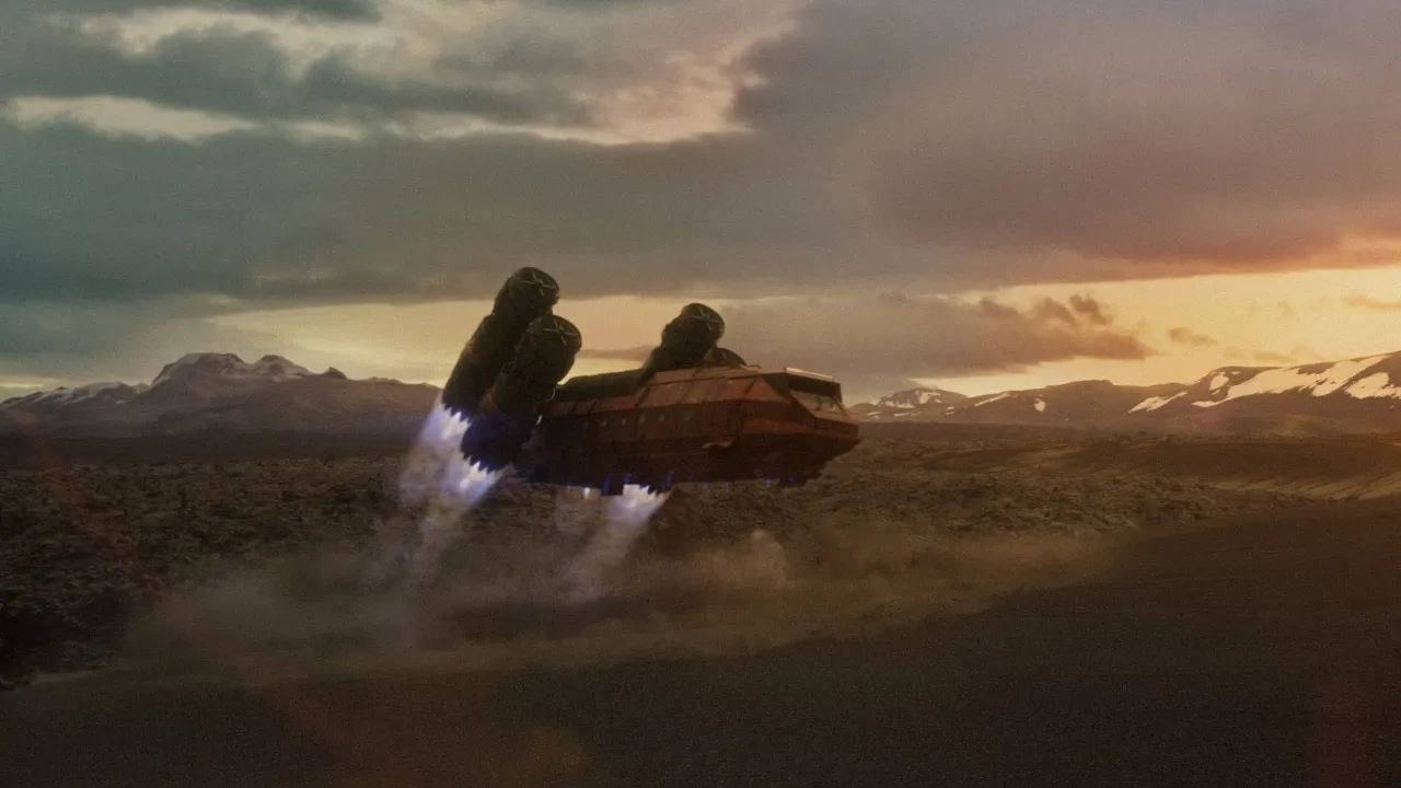 A futuristic spacecraft hovers above a rugged, barren landscape at sunset, with its engines emitting a glowing blue thrust, while distant mountains and dramatic clouds create a striking background.