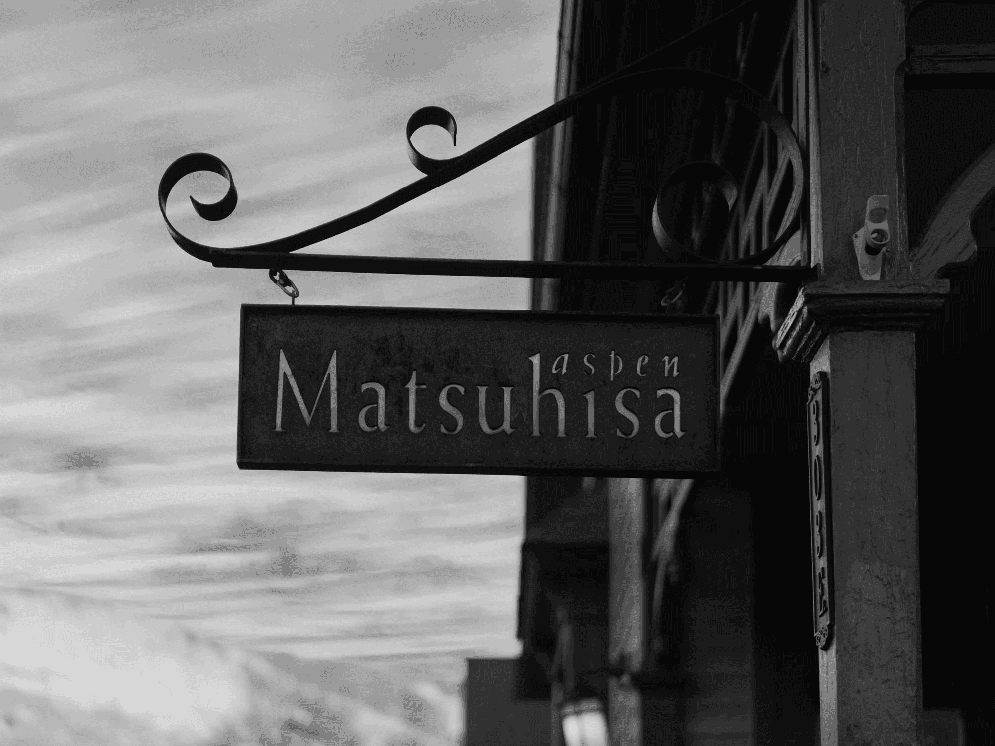 Black and white image of people working at a table with laptops, showing hands gesturing during discussion of digital content displayed on screens, with fabrica® logo in the corner.