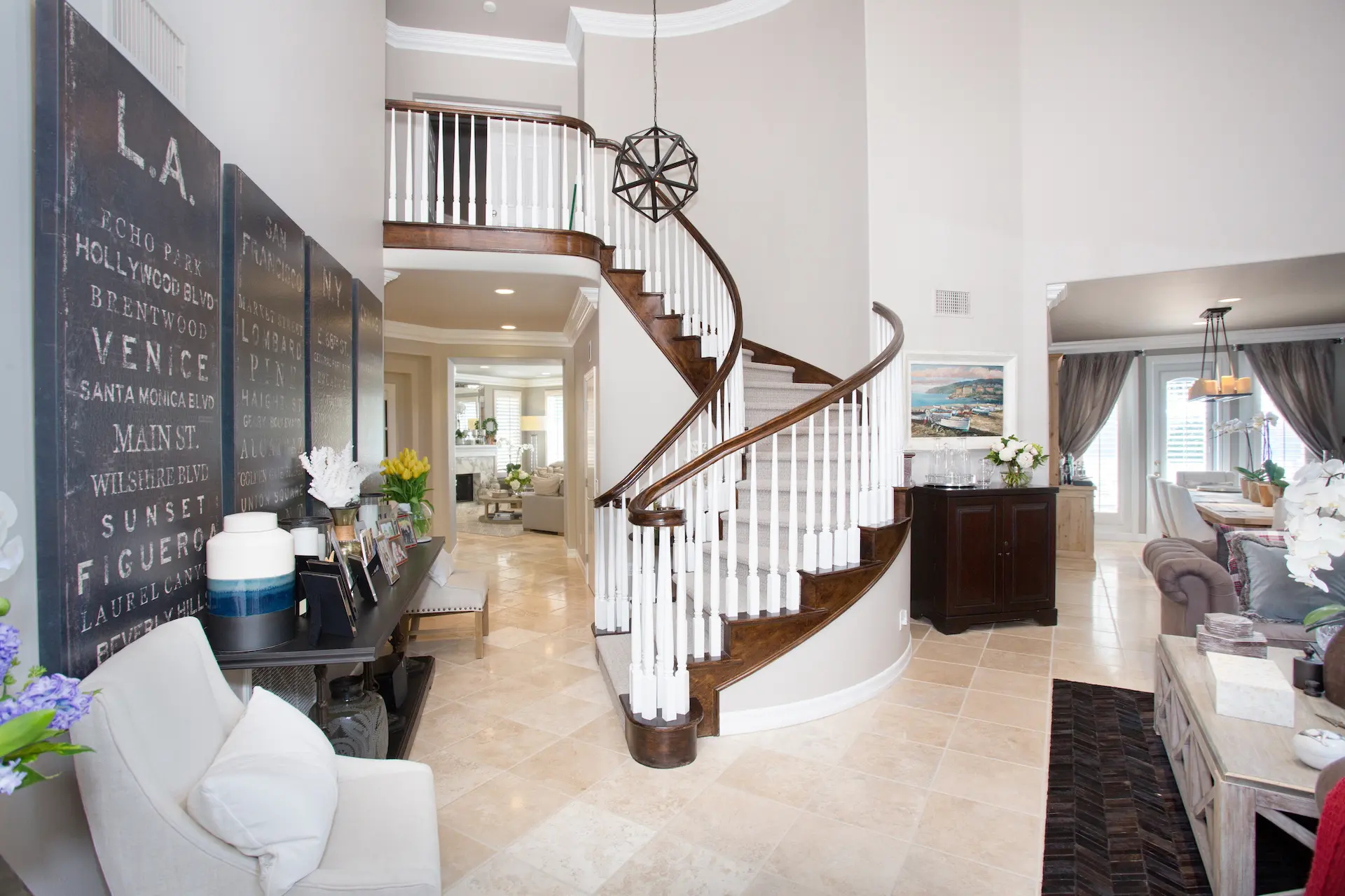 'Newport Beach Remodel' entryway with a spiral staircase, high ceiling, and an LA-themed chalkboard wall.