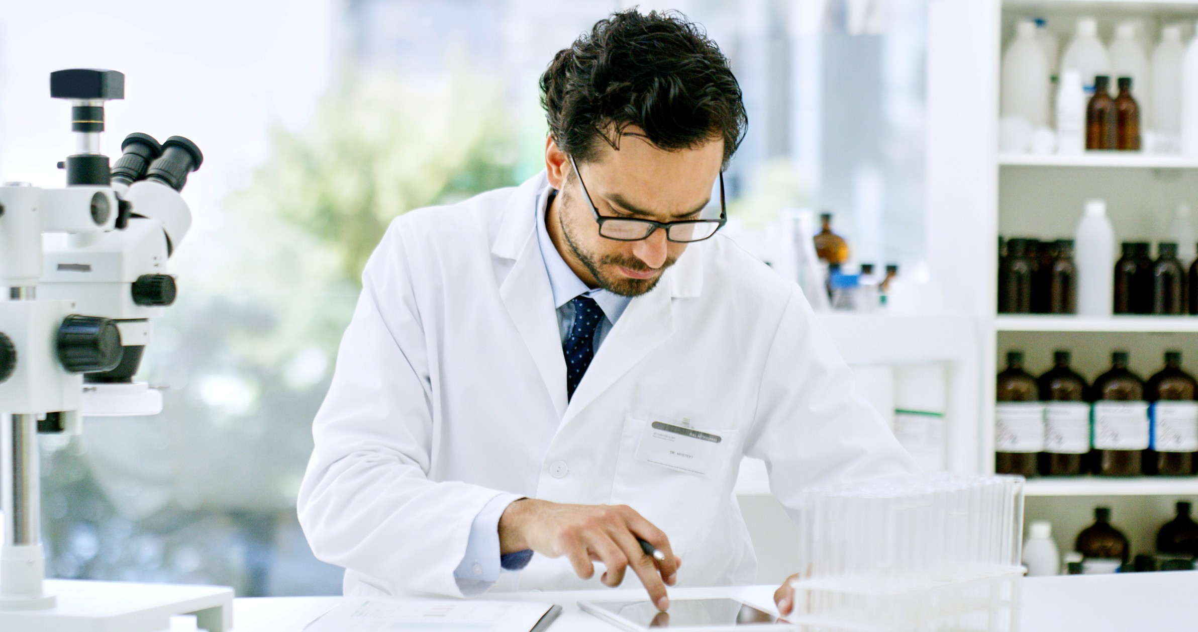 Confident female scientist standing with arms crossed in a cutting-edge laboratory filled with advanced scientific equipment.