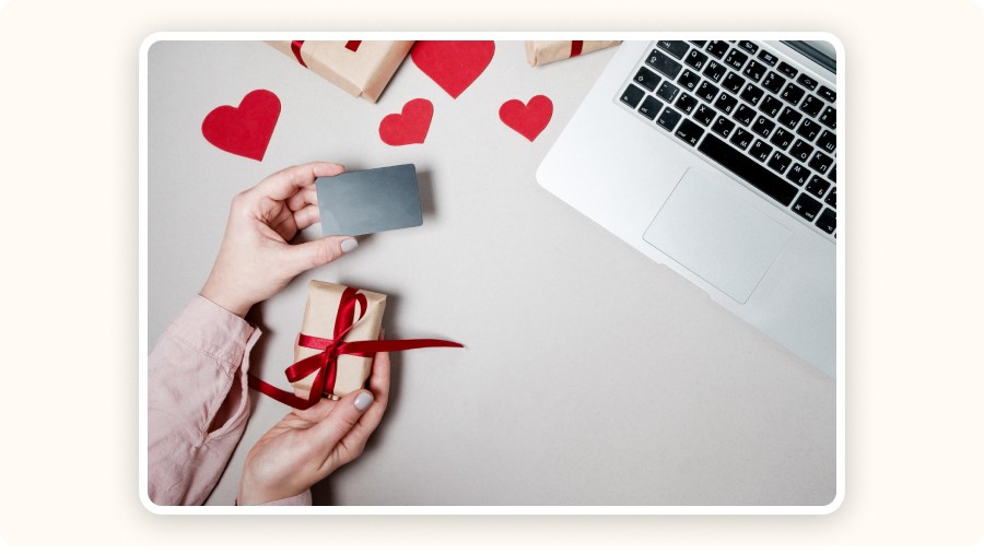 Online gift shopping scene with card, laptop, and red hearts.