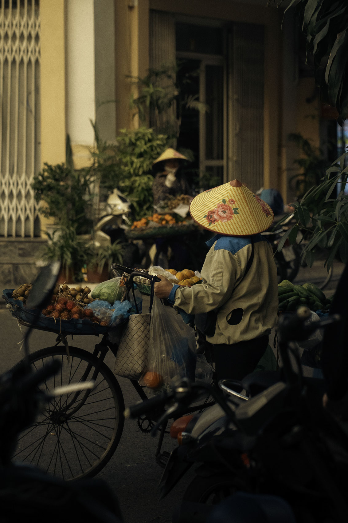 Femmes à vélo vendant des fruits et légumes dans une rue de Hanoï au Vietnam, photographie de voyage par Robin Masson