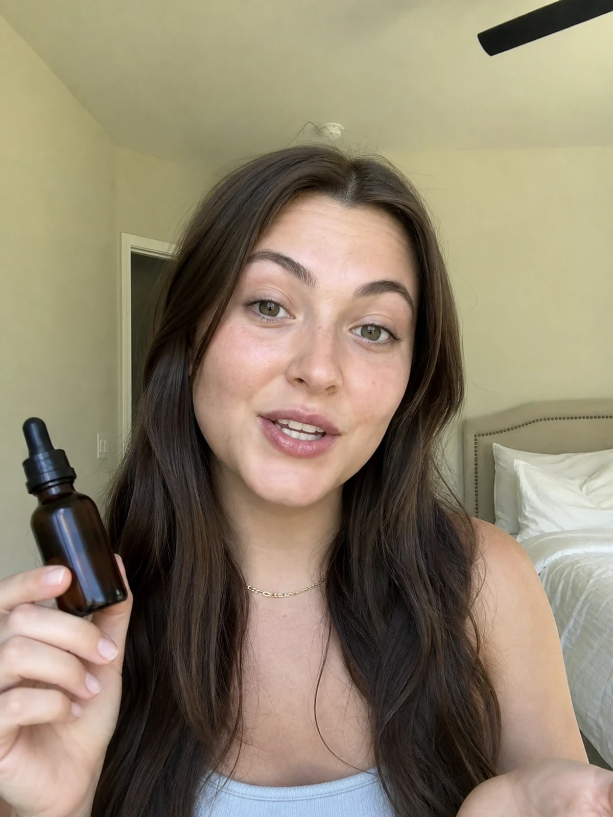 UGC creator in a clean bedroom, holding a simple wellness product and talking to camera.